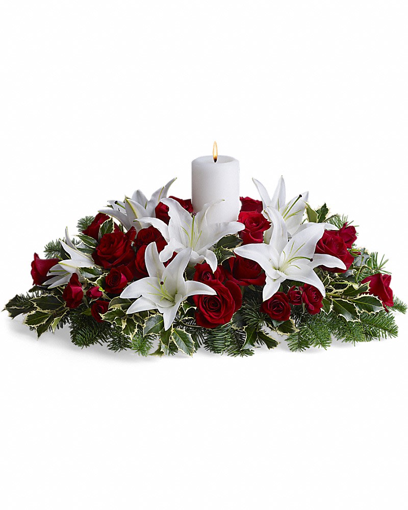 Luminous Lilies Centerpiece - Fragrant and fabulous, this luxurious Christmas dinner centerpiece is sure to earn &quot;oohs&quot; and &quot;aahs&quot; at your family get-together! Stunning white asiatic lilies hint of freshly fallen snow against Christmas greenery and lush red roses. Classic Christmas colors and holiday cheer are echoed in this beautiful centerpiece of red roses, white asiatic lilies, noble fir and holly branches. A single white pillar candle adds subtle glow.