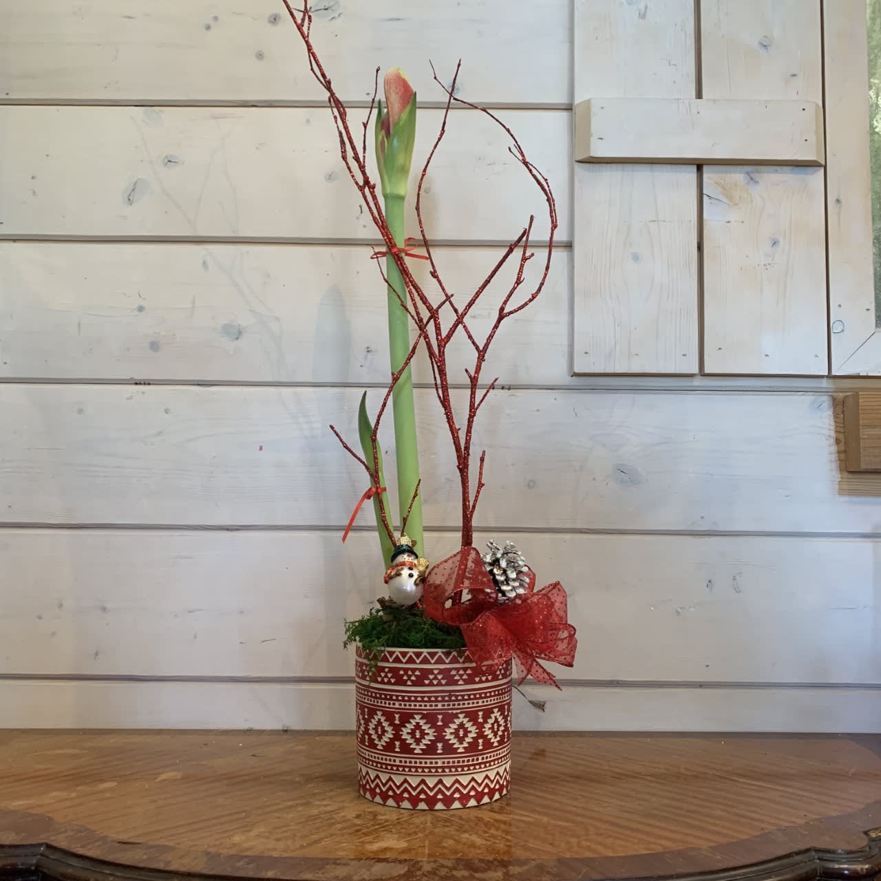 Christmas Amaryllis  - Amaryllis planted in a festive red Swedish pot with red glitter branches, pinecones and a bow. Includes small snowman ornament. 