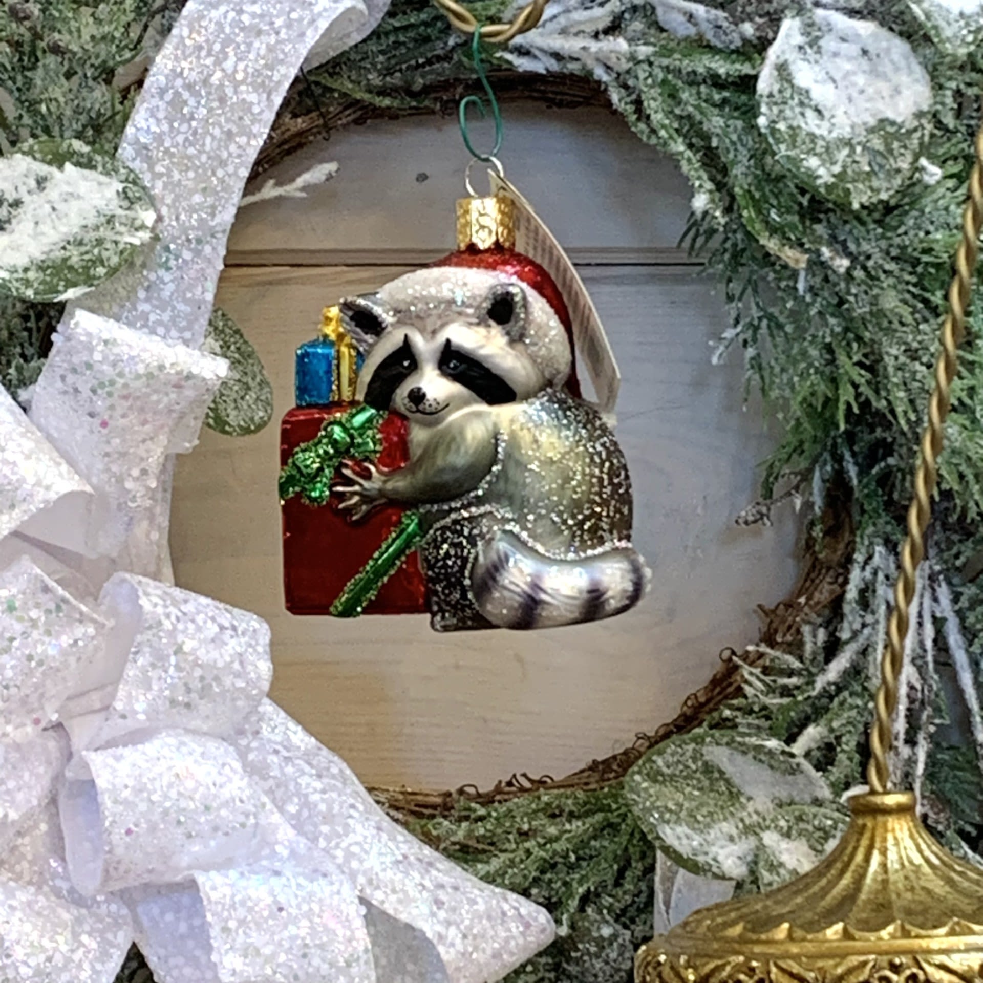 Christmas Bandit Raccoon Ornament - Watch out for the newest Christmas Bandit, Mrs Raccoon. A creature of the night, she can quietly sneak in to steal gifts from good boys and girls while remaining disguised in her natural bandit mask. Lock your doors and be on the lookout for this year's thief!   Approximately 2.5&quot; tall and 2.5&quot; wide.  Each figurative glass ornament produced by Old World Christmas is hand crafted in age-old tradition using the same techniques that originated in the 1800s. Molten glass is mouth-blown into finely carved molds made exclusively for Old World Christmas, before a hot solution of liquid silver inpoured inside. The ornaments are then hand-painted and glittered in a series of labor-intensive steps to achieve our beautiful creations.  Wreath and Tree Branch not included.   For more ornaments please check out our store at 3882 Mayberry Dr Ste A, Reno, NV 89519   