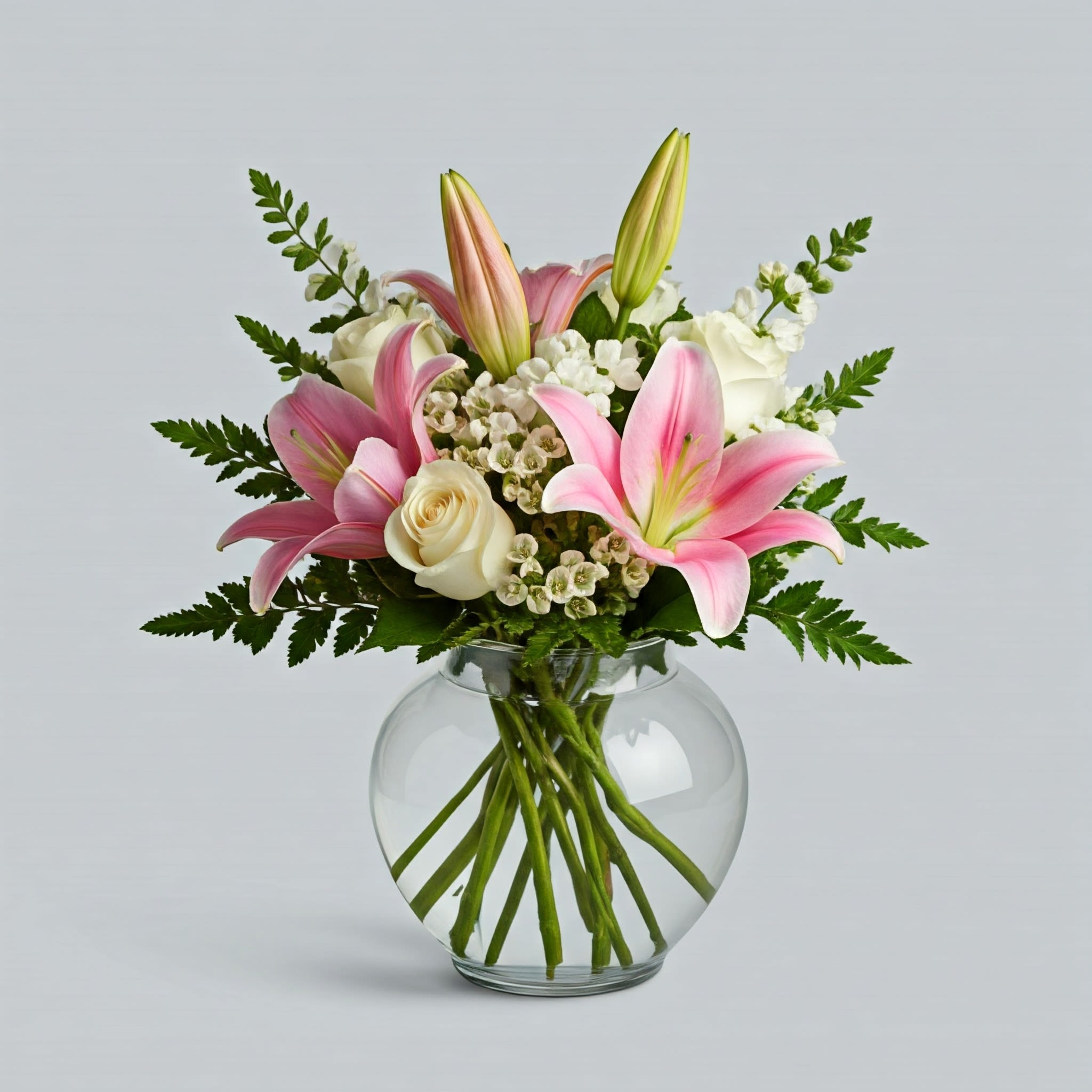 Elegance in Bloom - Elegance in Bloom  Indulge in timeless beauty with our exquisite round arrangement. A masterpiece of floral design, this composition showcases the delicate allure of oriental lilies, complemented by the pristine elegance of white and roses. Luxurious greenery completes this harmonious ensemble, creating a truly breathtaking display.  Whether it's a birthday, anniversary, or simply a gesture of love, this arrangement exudes sophistication and grace. Presented in a stylish bubble bowl or a classic cylinder vase, it's a versatile centerpiece that effortlessly elevates any space.  Experience the epitome of floral luxury with our Elegance in Bloom arrangement.  Approximate Dimensions: 10&quot;D x 12&quot;H