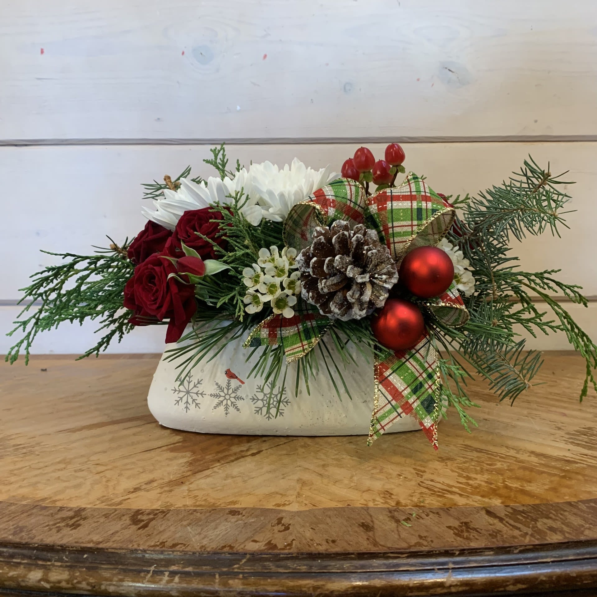 Christmas Memories Centerpiece - Burgundy spray roses, red hypericum and white cushion chrysanthemums arranged in a oval pot with cardinal motif with seasonal filler flower, plaid bows, glitter pinecones, and red ornament balls. Approximately 11&quot; long, 6&quot; wide, and 7&quot; tall.