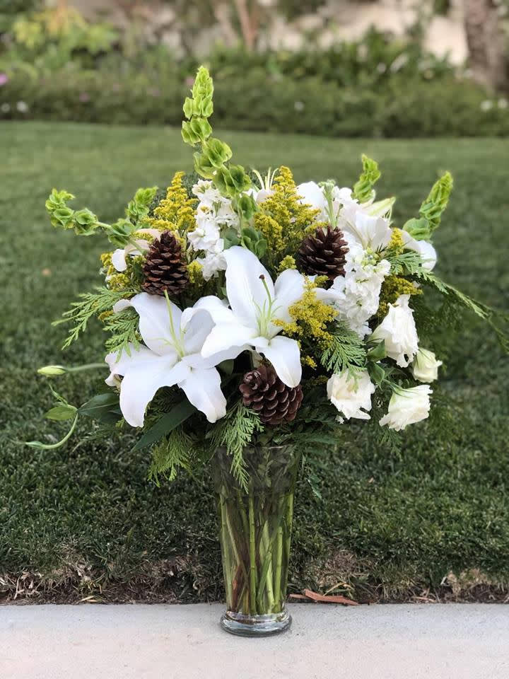 Holiday Lilies And Pines - An elegant holiday bouquet with lilies and pinescones! Perfect gift for Christmas and New Year!   Approximately 22" H x 16" W 