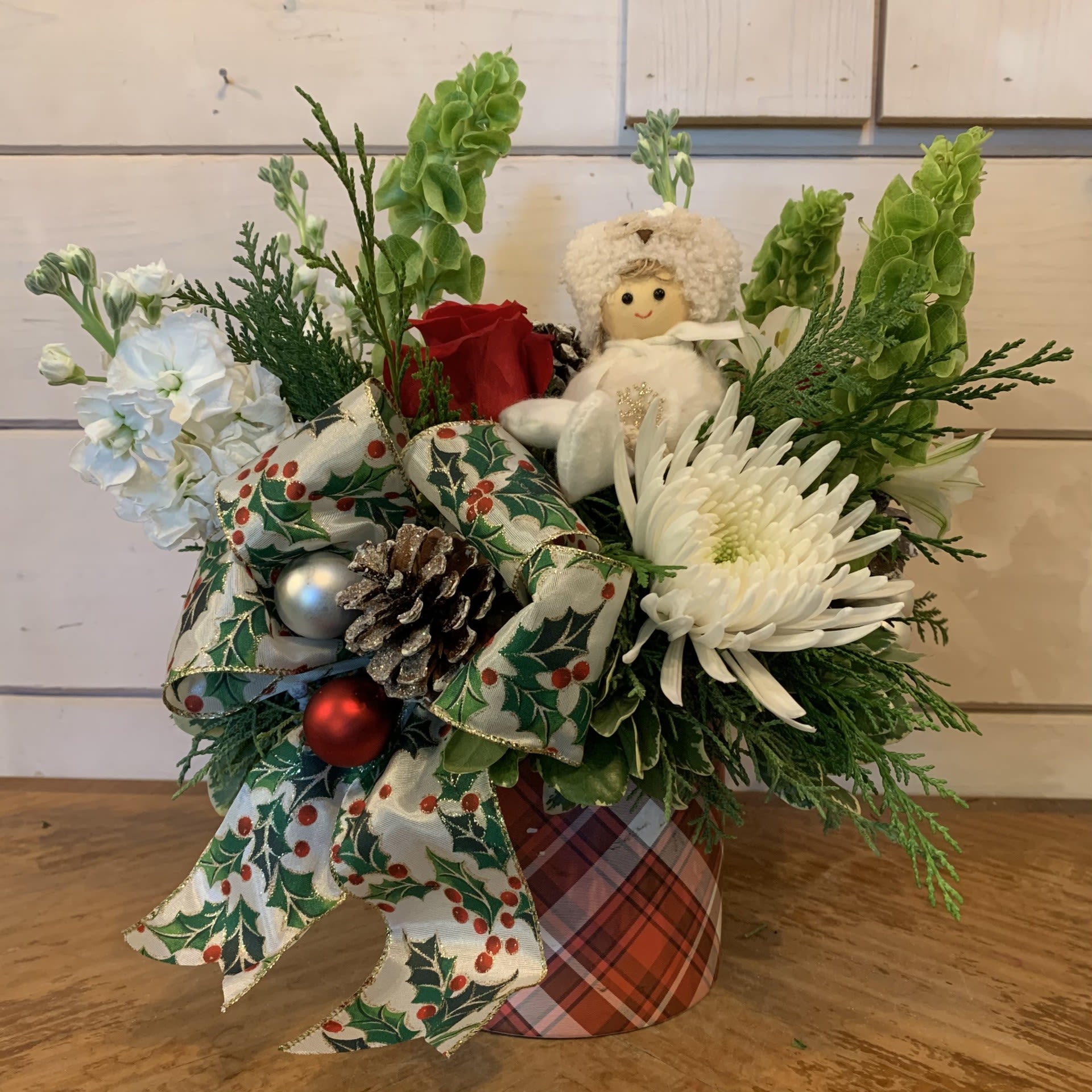 Let it Snow!  - Red roses, white cremon chrysanthemum, green bells of ireland, white stock, and white alstroemeria arranged in a regency plaid pot with a girl in an owl hat ornament, a large holly bow, glitter pinecones and red and white ornament balls. Approximately 12&quot; tall and 11&quot; wide.