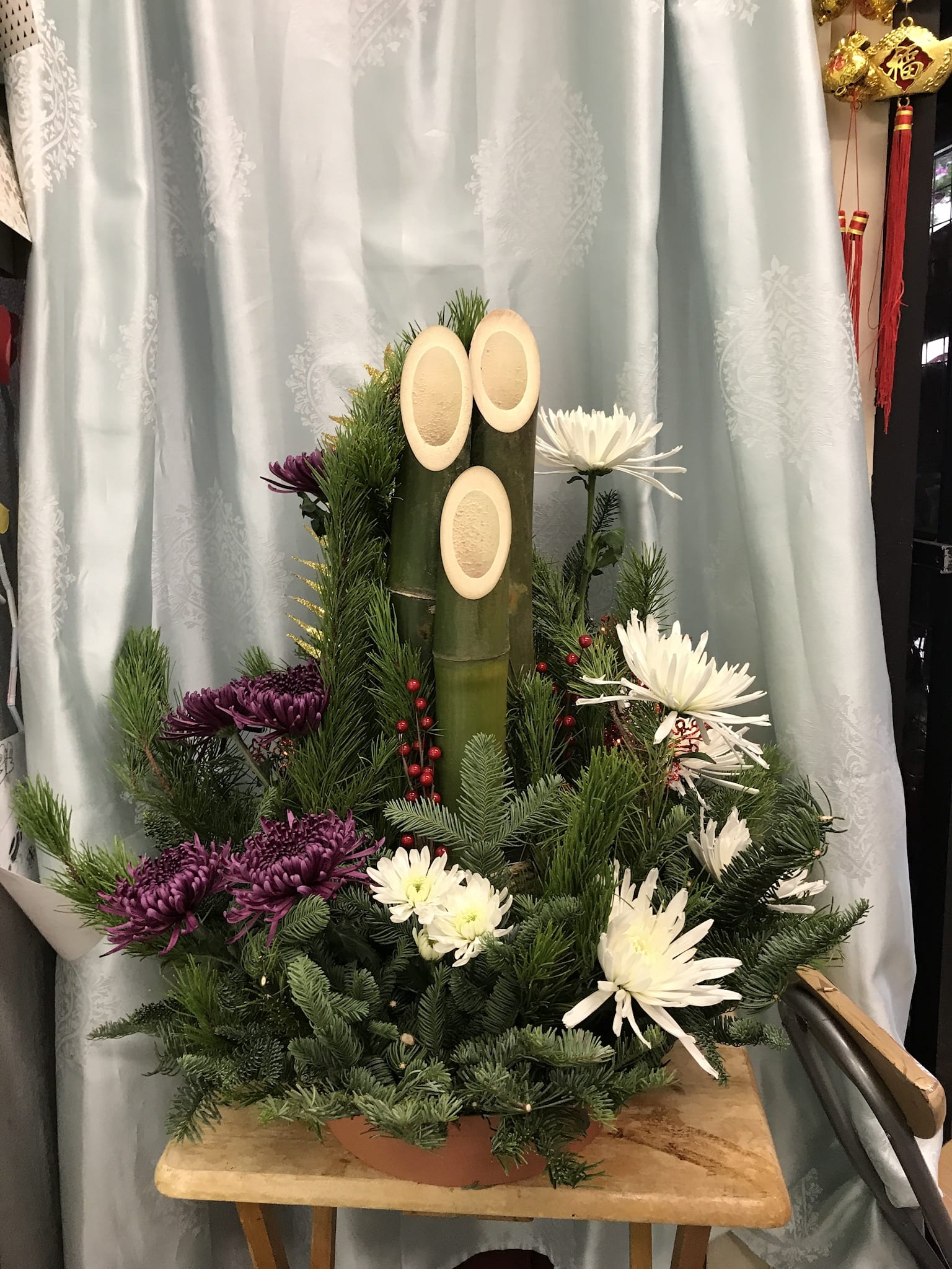 Holiday Mums and Kadomatsu  - Formal and elegant spider mums paired with stately Kadomatsu bamboo with holiday decorations sparkles gives your foyer an inviting grand entry or conversation piece for your dinner party