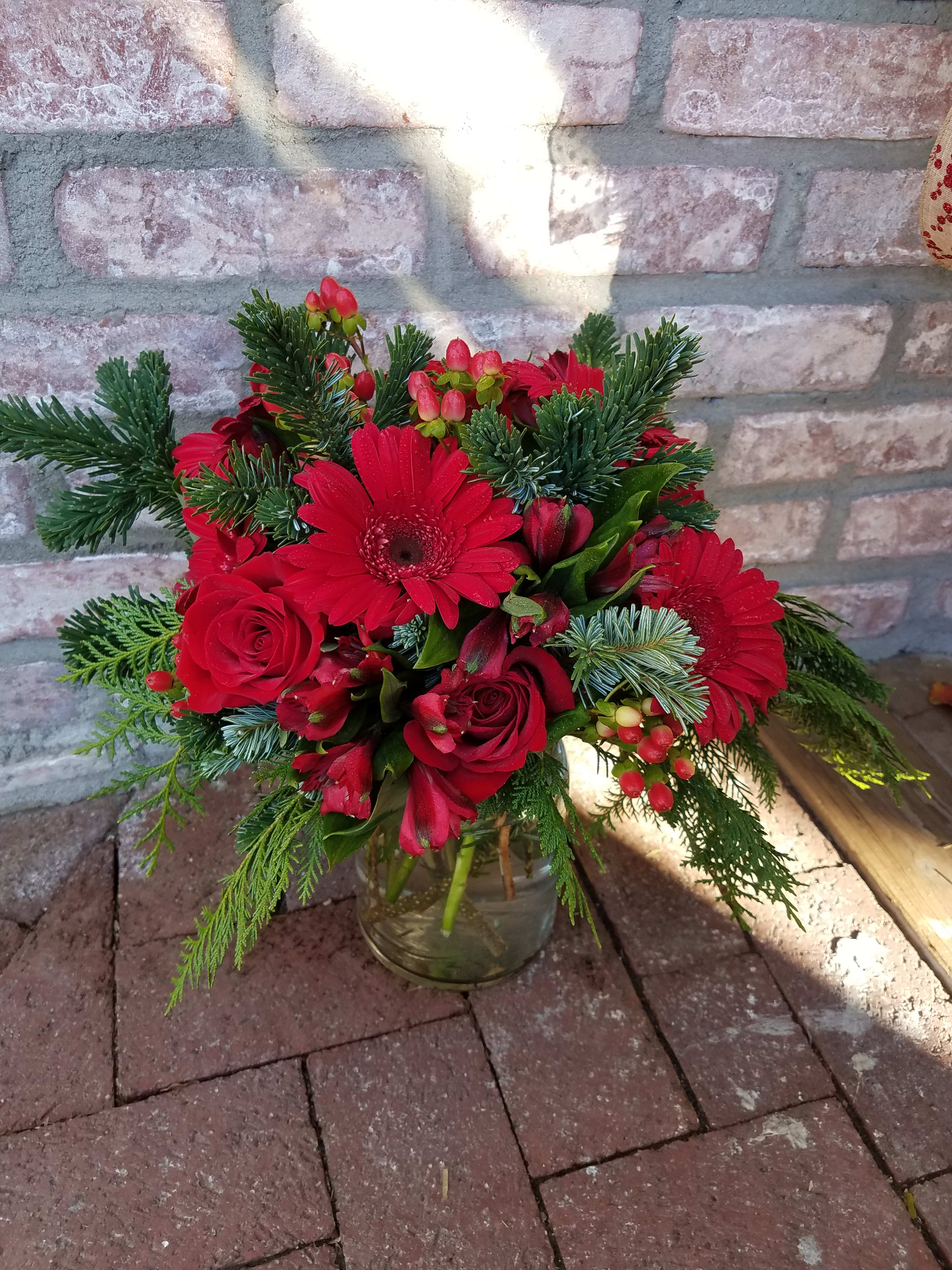 Classic Christmas - A fresh and fragrant design of yummy smelling fresh evergreens with a bold pop of reds make up this classic Christmas arrangement. 