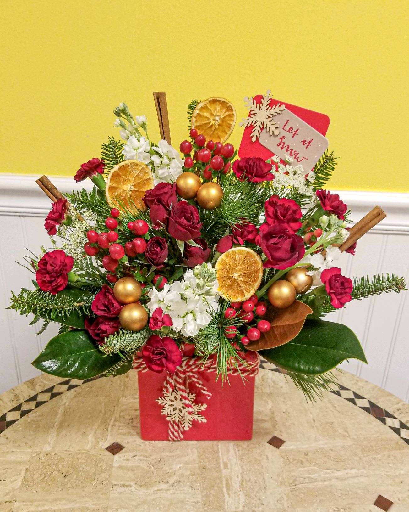 Let it Snow - Red Christmas present filled with the fresh holiday wintergreens and blooms.  **Please note, this is arranged one sided, ***