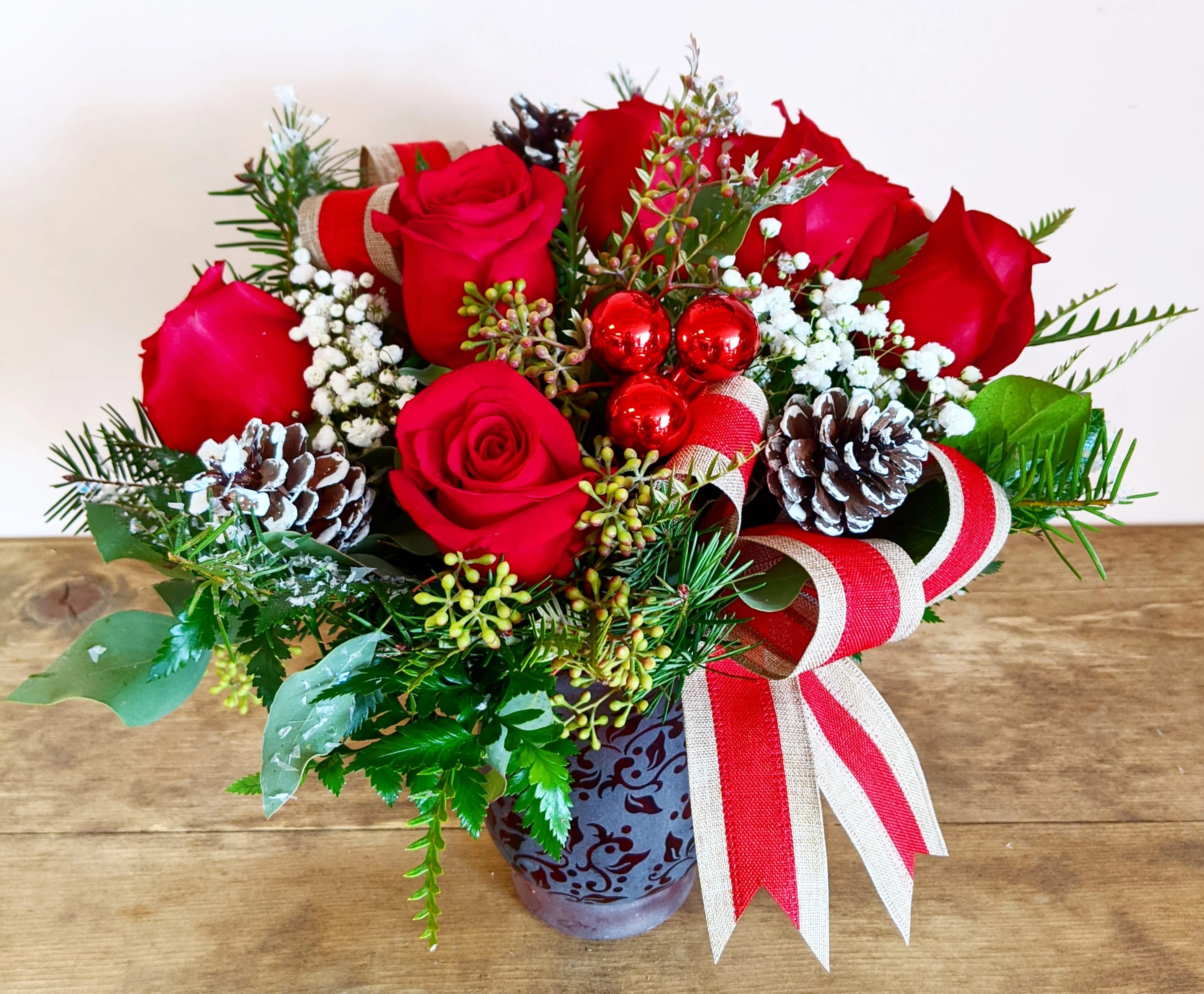 Country Rose Bouquet - Red vase with half dozen roses, babies breath, pine cones, holiday ribbon and glass ornaments in a red vase. Vase and ribbon may vary.