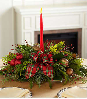 Christmas Callings Holiday Centerpiece - The Christmas Callings Holiday Centerpiece offers a classic holiday style that speaks to the heart of the yuletide season. Bringing together bright green Christmas greens and red and gold accents, as well as, a traditional holiday bow, this centerpiece is sure to bring light and love to any holiday gathering. Arranged to surround a singe 7-inch red tapered candle, this gorgeous centerpiece will be that perfect accent piece for your Christmas table or create a great gift for friends and family across the miles. Your purchase includes a complimentary personalized gift message. Upgrades will include more accents and a larger size, and more candles (if specified). 
