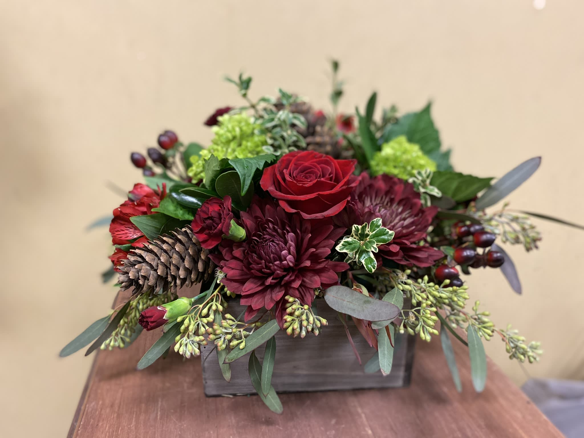 Red Holiday - Seasonal holiday florals with mixed evergreens, in a low profile wooden container