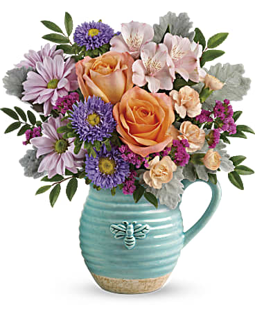 Busy Bee Pitcher Bouquet - Everyone's abuzz about this beautiful bouquet! Lush orange roses and delicate pink blooms look delightfully darling in this country-inspired, food-safe ceramic pitcher with petite bee motif. Peach roses, light pink alstroemeria, peach miniature carnations, lavender matsumoto asters, lavender daisy spray chrysanthemums, and raspberry sinuata statice are arranged with huckleberry and dusty miller. Delivered in the Busy Bee pitcher. Orientation: All-Around 