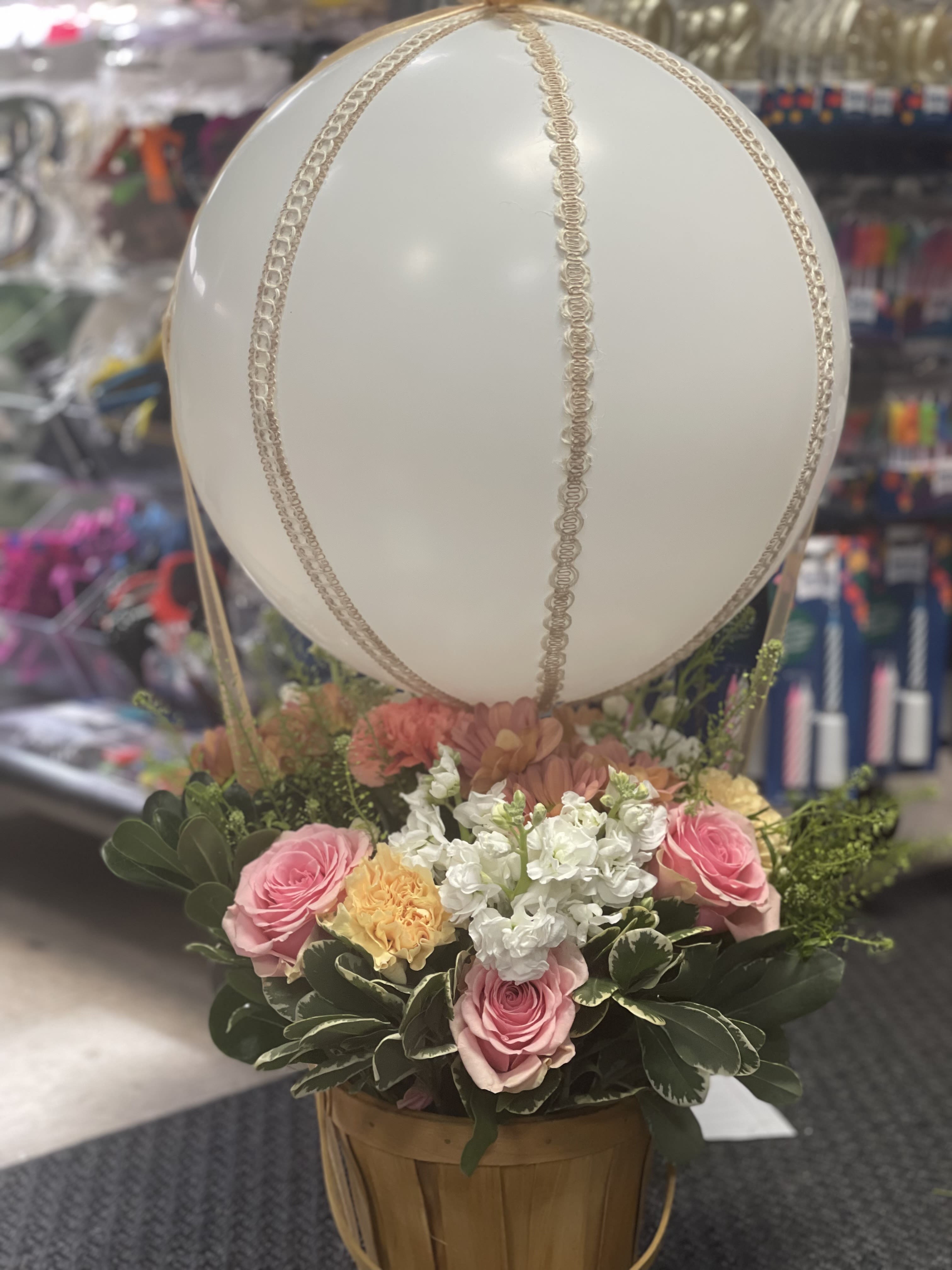Rose Balloon Bliss Arrangement  - Brighten any day with our charming Rose Balloon Bliss arrangement — a joyful display that lifts hearts and spirits. Nestled in a woven basket, soft pink roses take center stage, symbolizing grace and affection. They're beautifully complemented by cheerful yellow blooms and delicate white flowers, creating a fresh and uplifting palette. Floating above is a clear balloon, adding a whimsical, celebratory touch to this sweet and stylish piece. Perfect for birthdays, congratulations, or simply to make someone smile. 