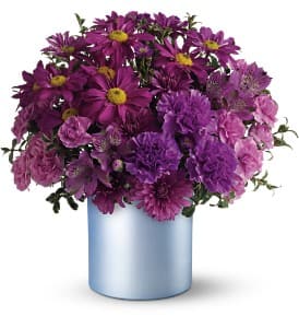  Vivid Violet Bouquet - Shockingly chic, this dramatic bouquet in a soft blue cylinder vase is a study in contrasts. Surprise a friend who appreciates things with a bit of an edge. They'll be wild about it.  The radiant arrangement includes lavender daisy chrysanthemums, alstroemeria, purple cushion chrysanthemums, purple carnations, purple miniature carnations and purple Monte Cassino accented with Oregonia.   Delivered in a stylish ceramic cylinder vase with a light blue satin finish.   Bouquet is approximately 14” W X 14” H  Orientation: All-Around