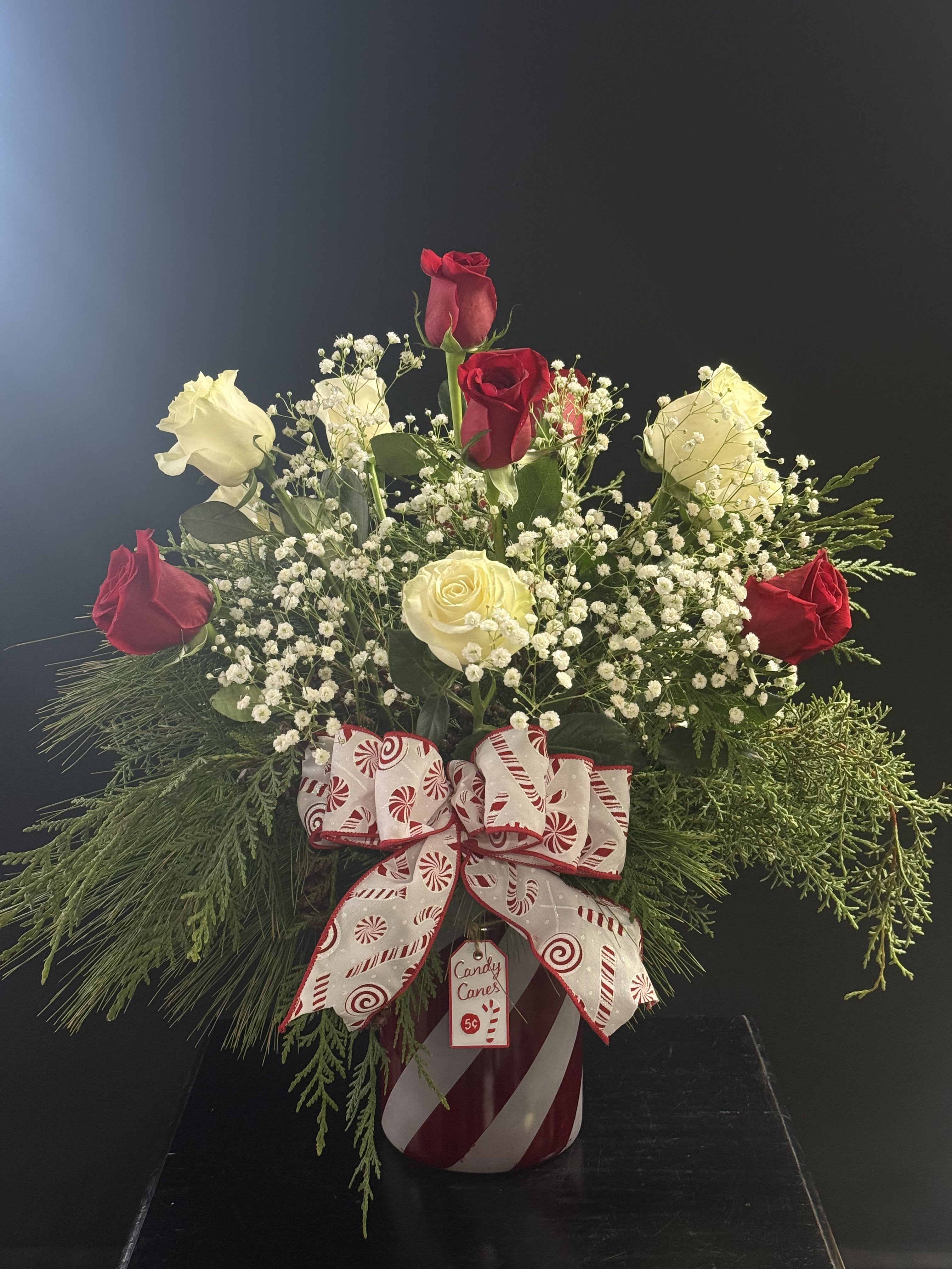 Candy Cane Dozen - A mix of red and white roses with beautiful wintergreens in a cute red and white candy cane vase.