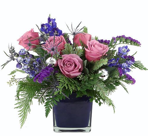 Frosted Twilight  - The Frosted Twilight Bouquet captures the magic of a winter evening with its blend of cool purples, silvers, and evergreens. Featuring elegant mauve roses and rich violet blooms arranged in a deep blue glass vase, this chic design brings a touch of holiday charm and sophistication to any space. Perfect for gifting or brightening your own winter décor.