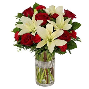 Dazzling Holiday Rose &amp; Lilies Bouquet - Dazzling is indeed the perfect adjective to describe this beguiling holiday arrangement. Vivid roses, Asiatic lilies and carnations are placed in an elegant glass cylinder vase. Completing the joyous holiday look is a shimmering diamond wrap that adorns the container. 