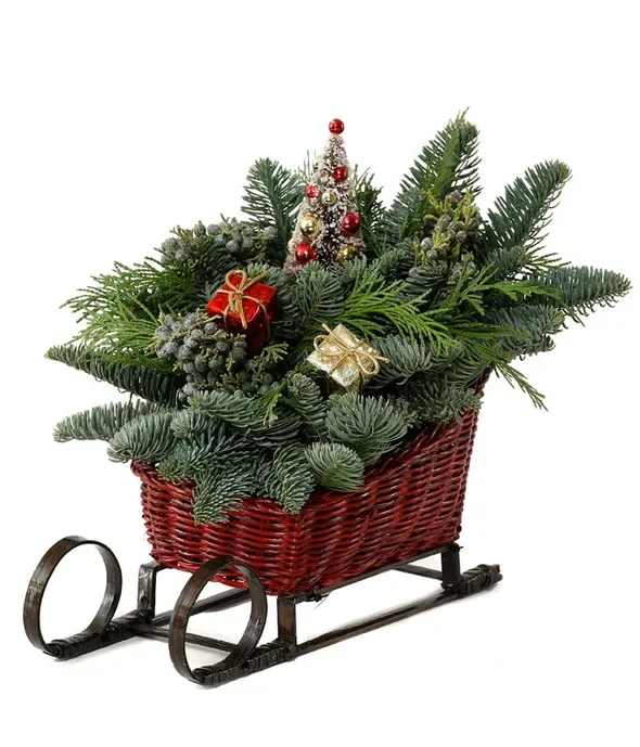 Sleigh Ride Centerpiece - A sleigh with a beautiful present for loved ones this season. Send them this centerpiece with noble fir, western red cedar, and juniper in a red sleigh basket with fun decorations of presents. It's a fun arrangement that will make them want to go out dashing through the snow.