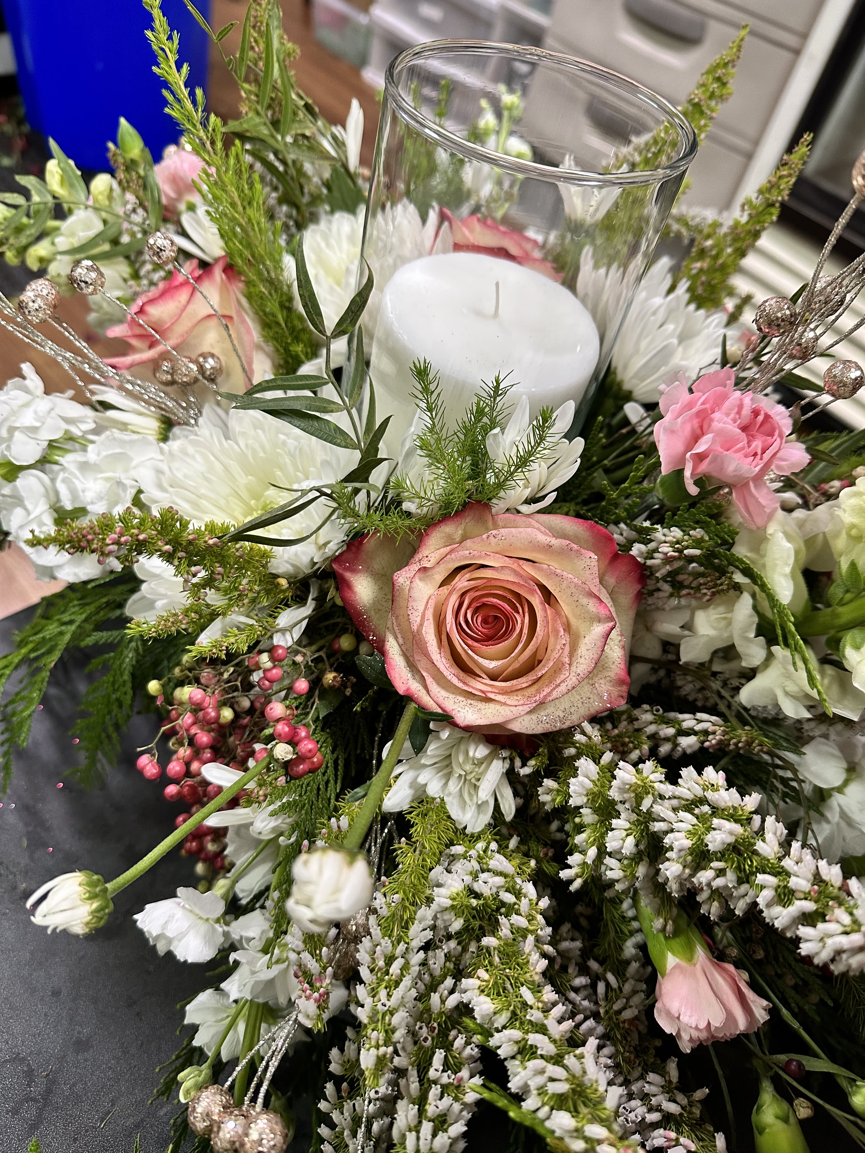 Pillar Candle Holiday Centerpiece - Beautifully designed holiday centerpiece with holiday themed florals and greenery adorned with a single white pillar candle