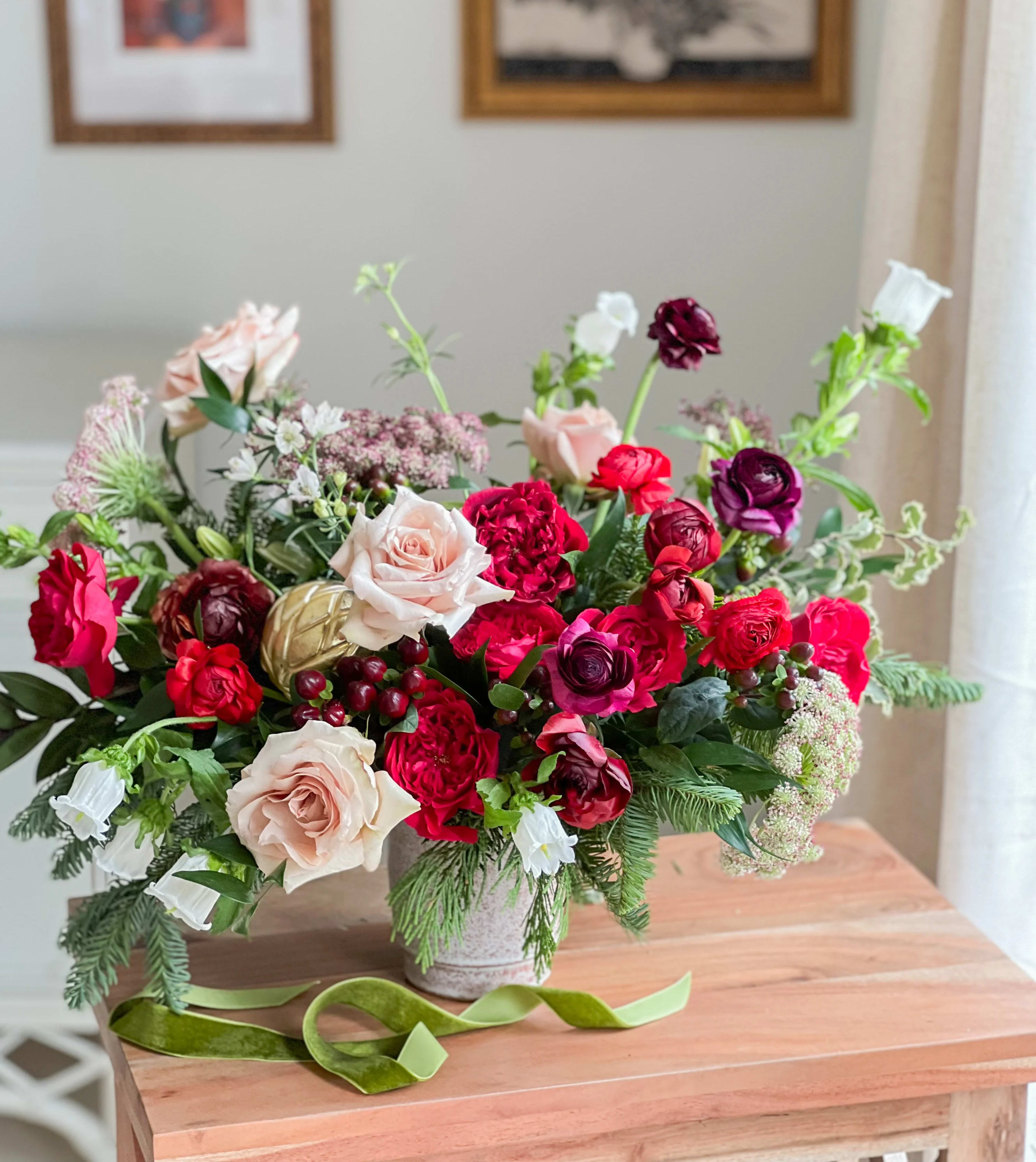 Holiday Designer’s Choice  - Seasonal fresh flowers in a red, burgundy, cream and green color palette with many beautiful textures.  Pictured is our deluxe size. 