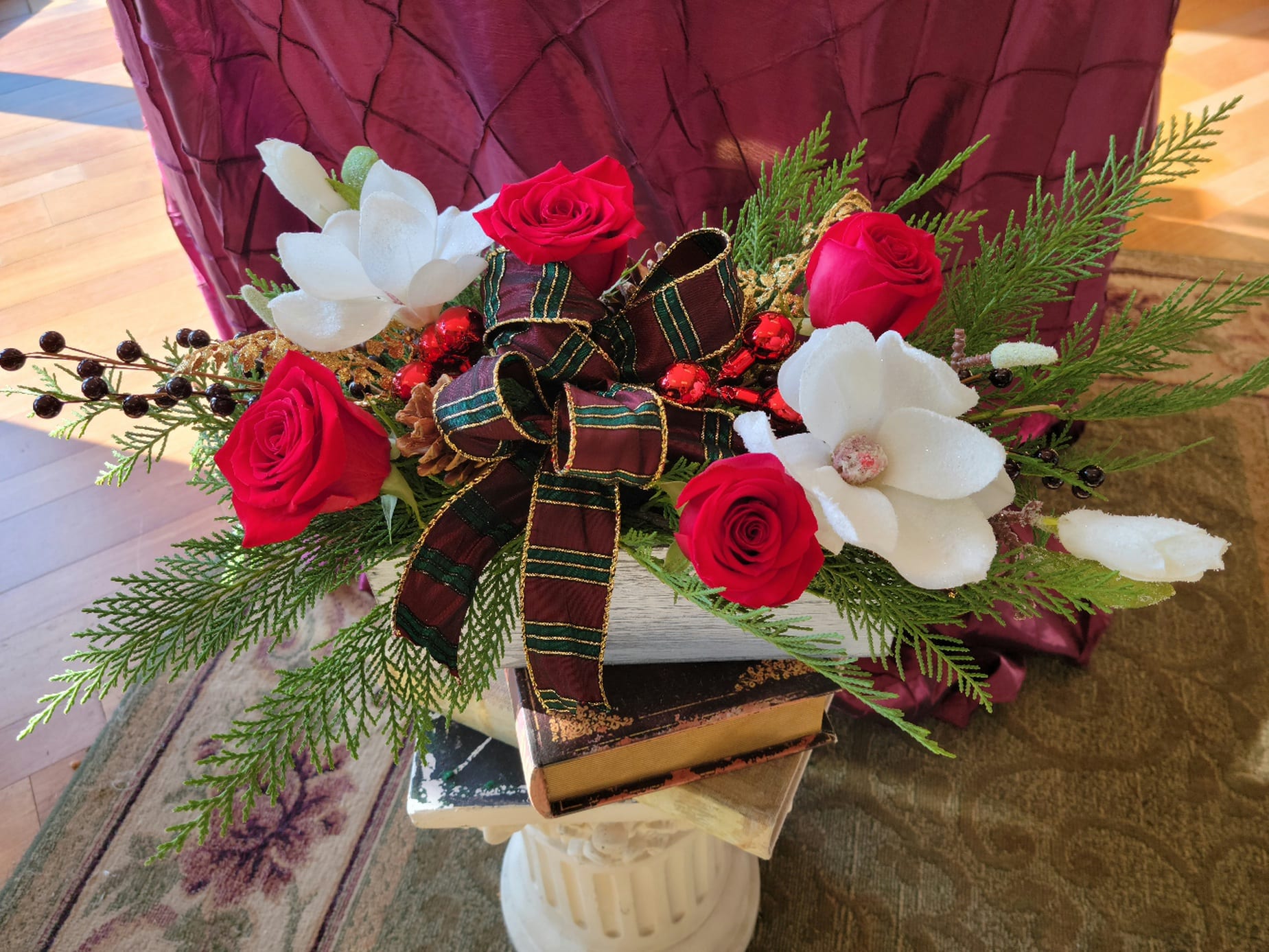Box of Christmas - Fresh Christmas greens and red roses accompanied by faux magnolias, berries, pinecones and ornaments topped with a beautiful bow...artfully arranged in a box.