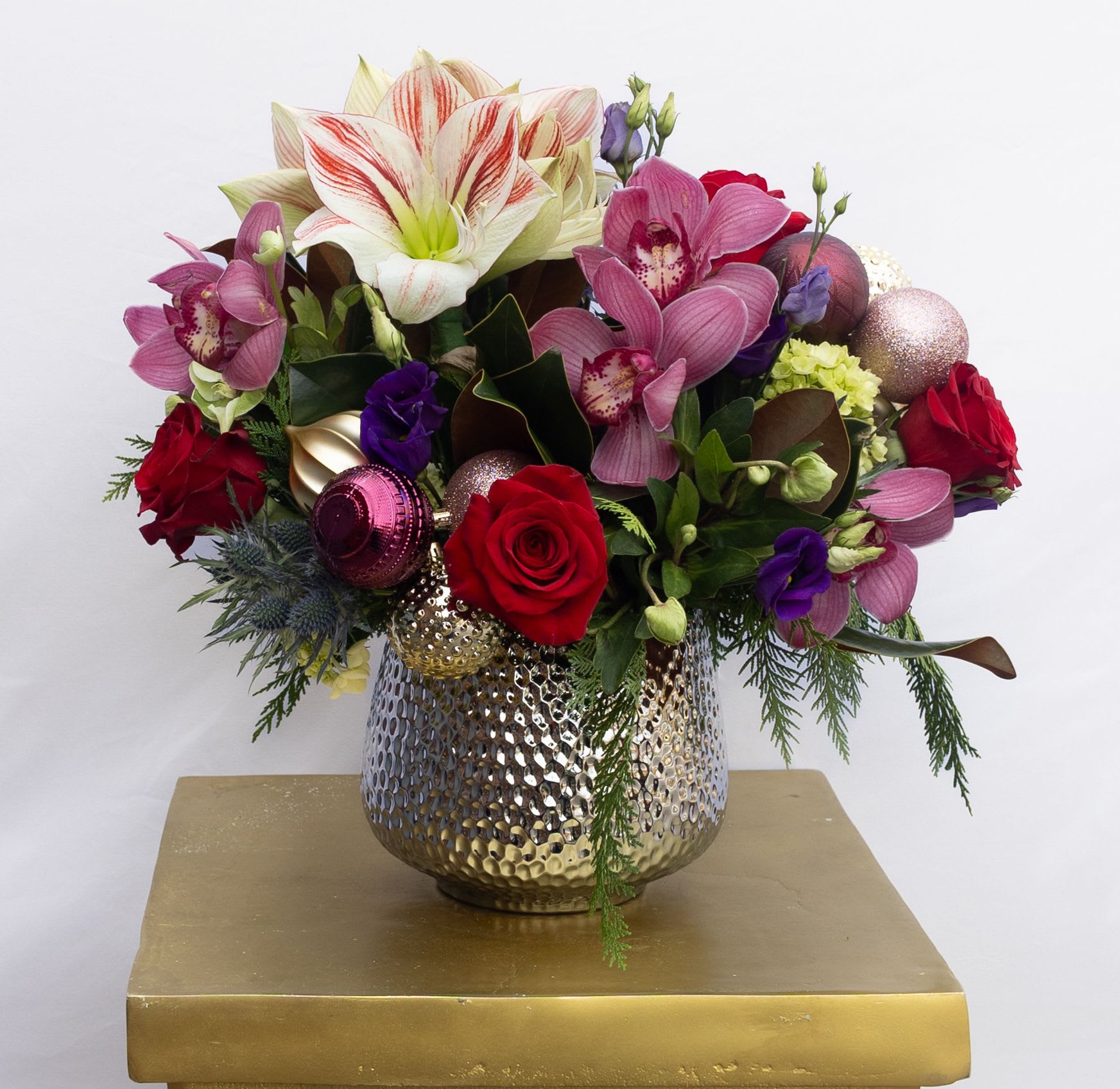 Holiday Jewel Tones - Mix of vibrant flowers accented with holiday ornaments. Flowers may include red roses, purple lisianthus, candy cane amaryllis, blue thistle and mini green hydrangea. 