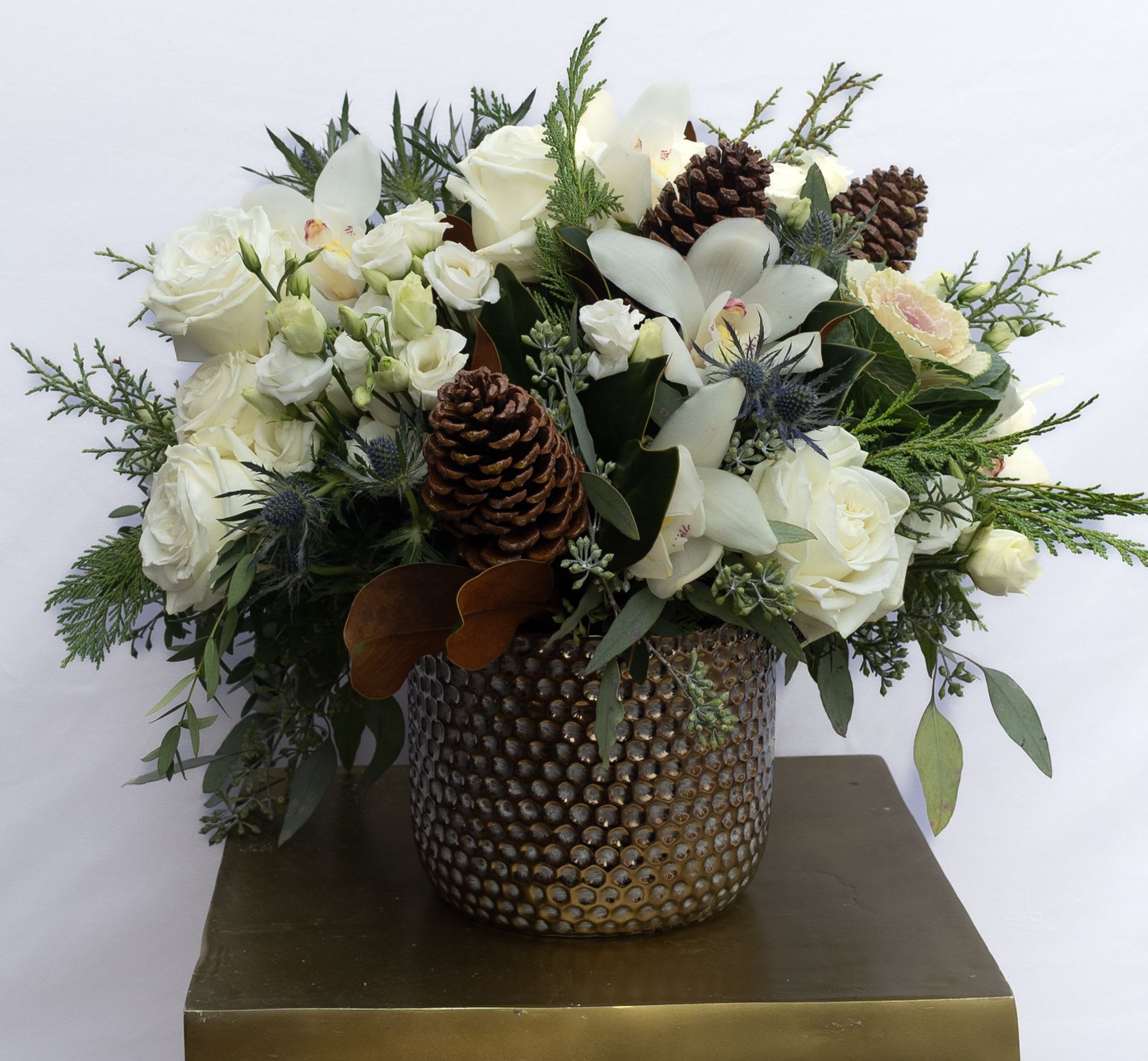 Winter Woodland White Mix - Mix of white flowers filled with rustic winter greenery. Flowers may include white roses, white Lisianthus, blue thistle, and white cymbidium orchids. 