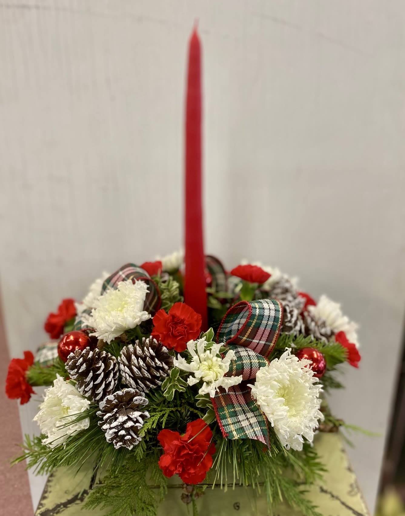 Light and Love - The Light &amp; Love Holiday Centerpiece adds that special touch to any seasonal gathering. White snowflake chrysanthemums and burgundy or red mini carnations are accented with lush holiday greens and bedecked with festive elements, gorgeously arranged around a red taper candle, to create a warm wish for a perfect holiday season.