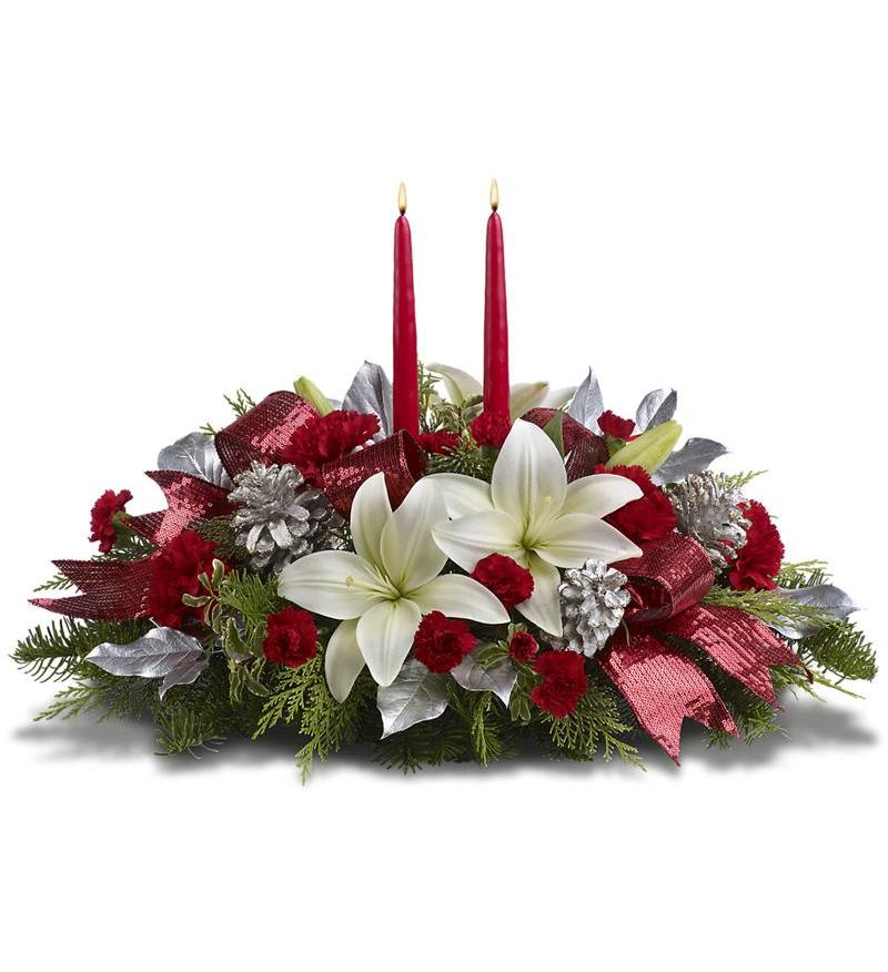 Christmas Splendor Centerpiece -  A beautiful holiday centerpiece with White Lily, Red Carnations, Silver Pine Cones, and Mixed Evergreens. Adorned with a bow and 2 holiday candles. 
