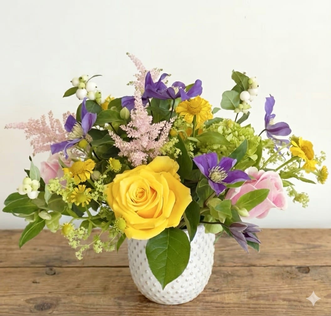 Summer Radiance - Brighten any space with the joyful elegance of our Summer Radiance arrangement. Bursting with vibrant colors and lush textures, this handcrafted bouquet features bold yellow roses, soft pink roses, delicate pink astilble, stricking purple clematis, and cheerful yellow daisies. Accented with fresh greenery, snowberries, and textural elements, the arrangement comes with artfully displayed in a chic white ceramic vase with a subtle textured finish.   Perfect for birthdays, celebrations, or simply to add a touch of summer charm to your home or office. Each arrangement is thoughtfully designed to bring a lasting smile.   Details:  *Approximated size: 10"W*9"H *Fresh, seasonal blooms for maximum vibrancy *Delivered in a reusable decorative vase  