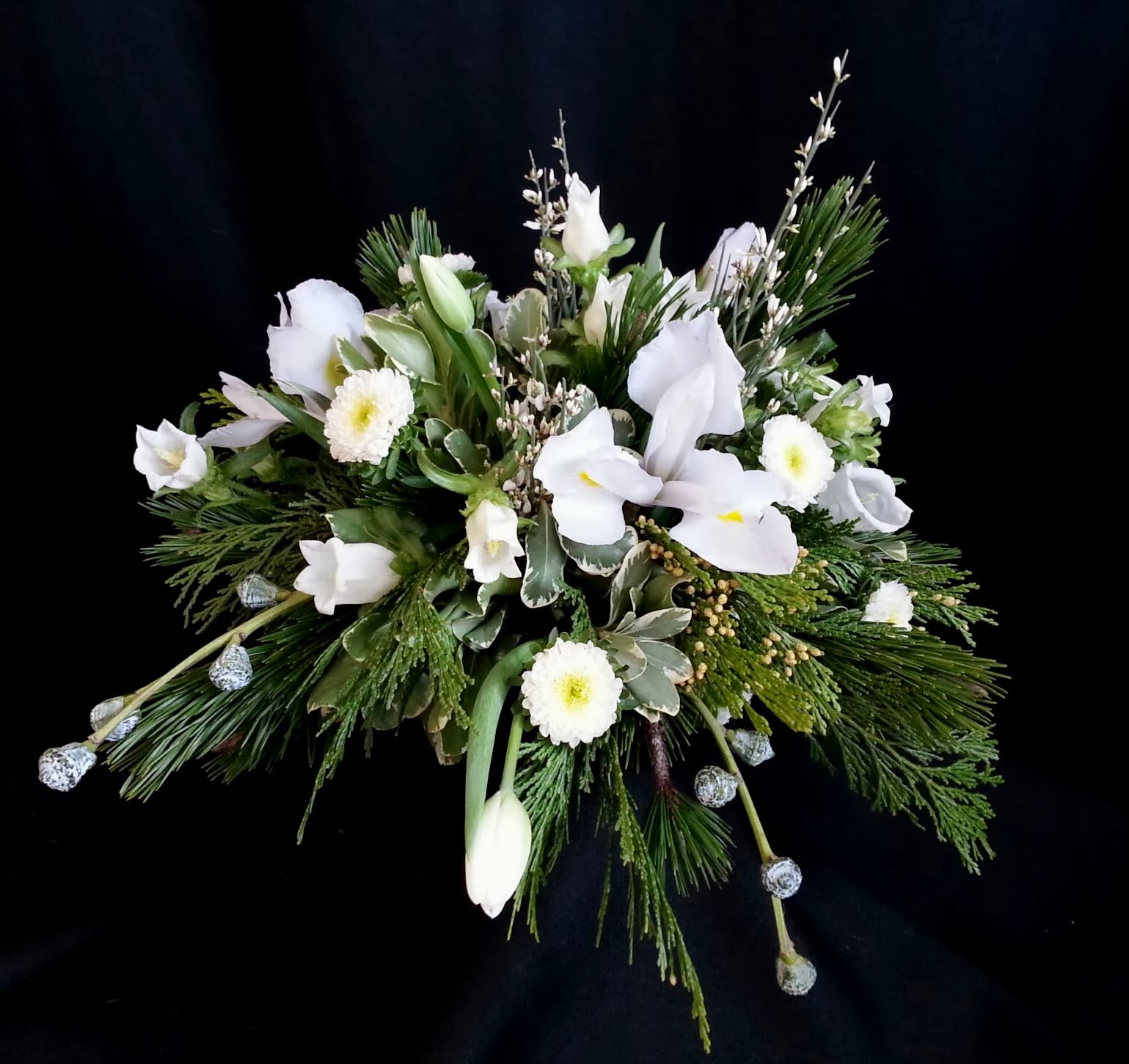 Centerpiece White winter wonderland tulips - Medium round and lovely centerpiece size shown is for your holiday dining table of up to 5 people.  We can INCREASE the size to fit a table of up to 12 or CUSTOMIZE TO MATCH YOUR HOLIDAY COLOR SCHEME. Just choose the Deluxe or Premium version to beef up your size!  Here you see silver bells eucalyptus berries, white tulips, matsumoto asters, iris and genestra.  Order WELL in ADVANCE if you would like us to reserve specific colors (including white).  