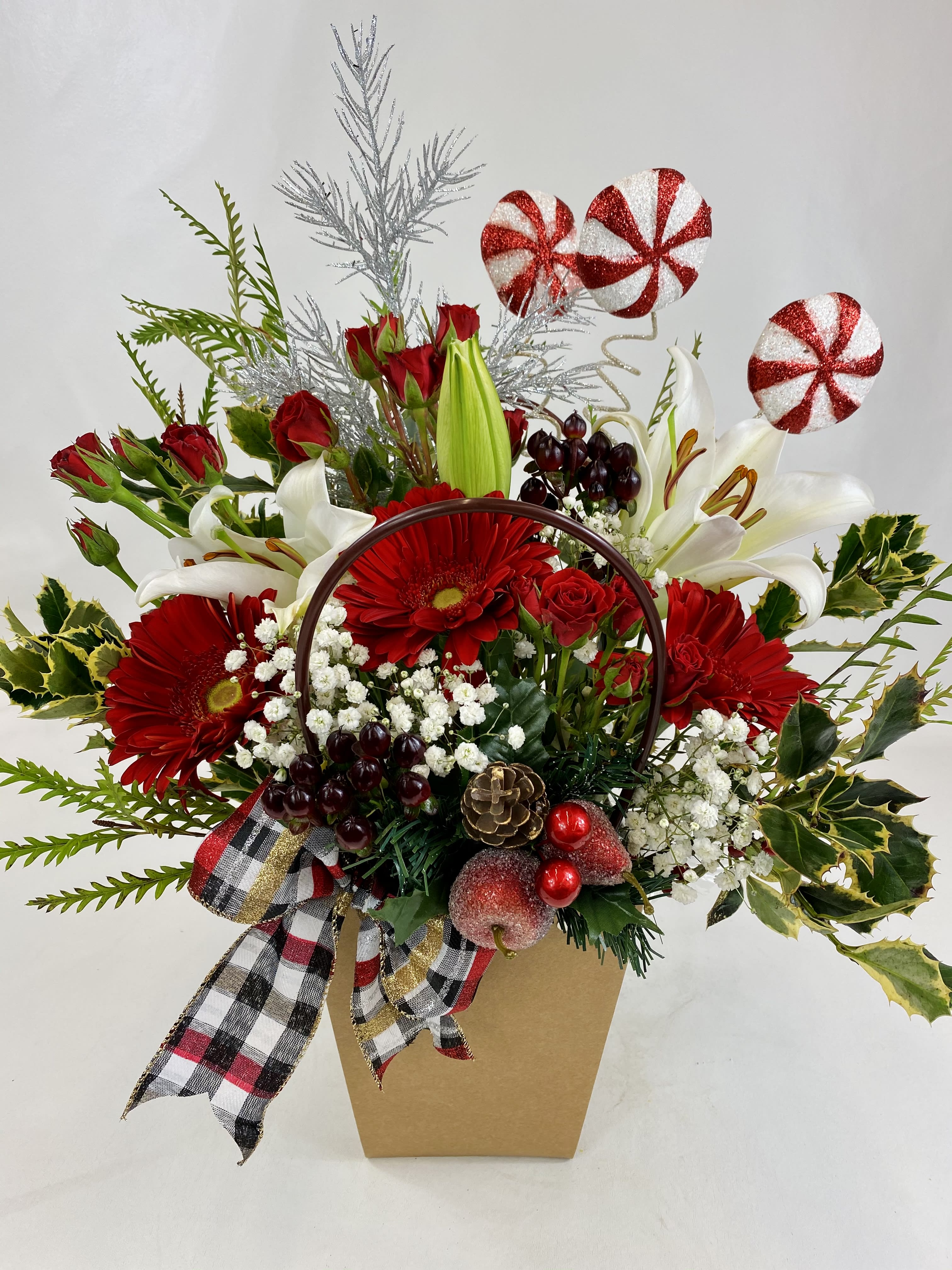 Holiday bag of wishes - Very unique holiday flower arrangement with gerbera daisies, spray roses, lilies, greenery and Christmas decorations 