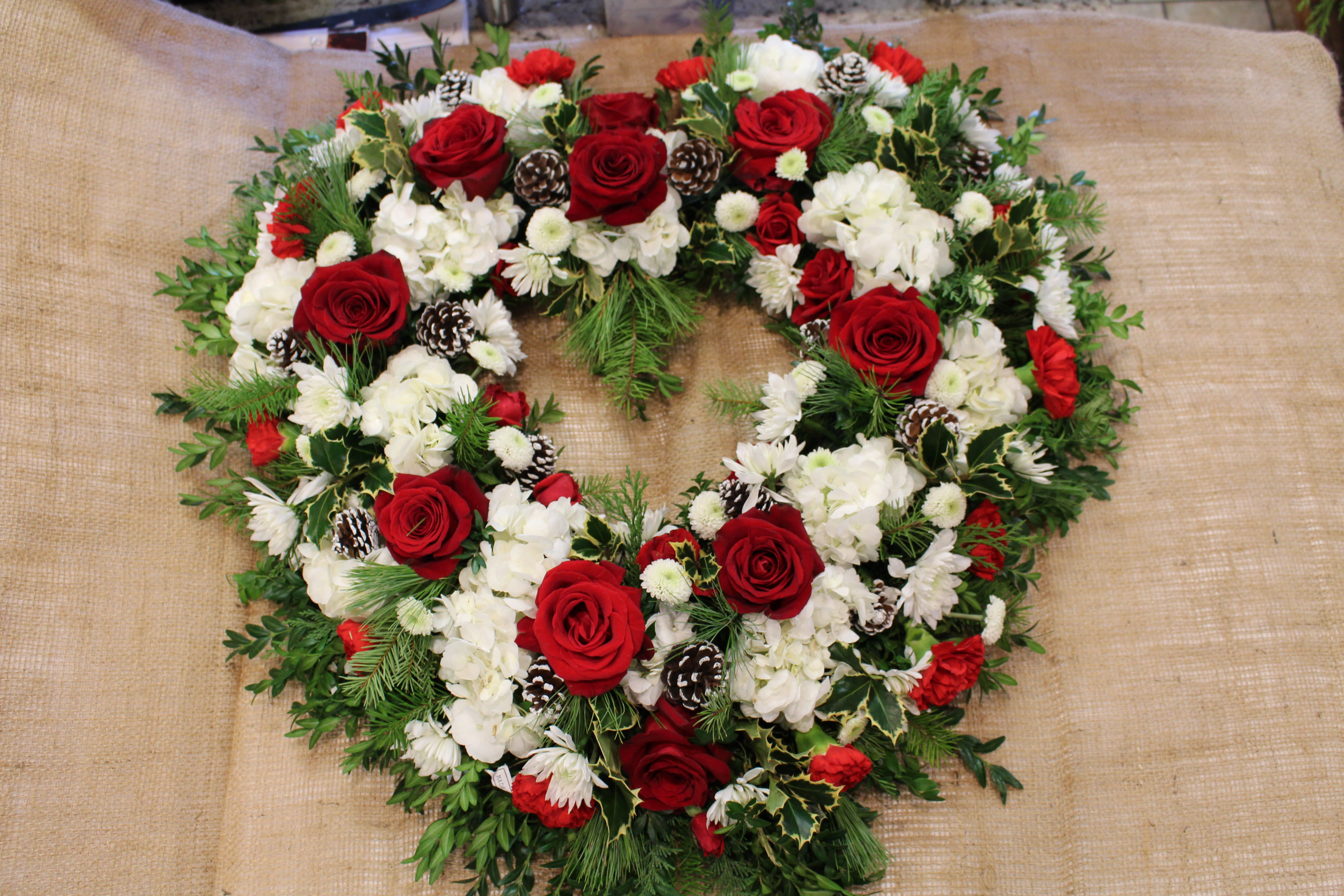 seasonal open heart - A beautiful arrangement of flowers shaped into a heart, seasonal greenery draped with roses, carnations and more