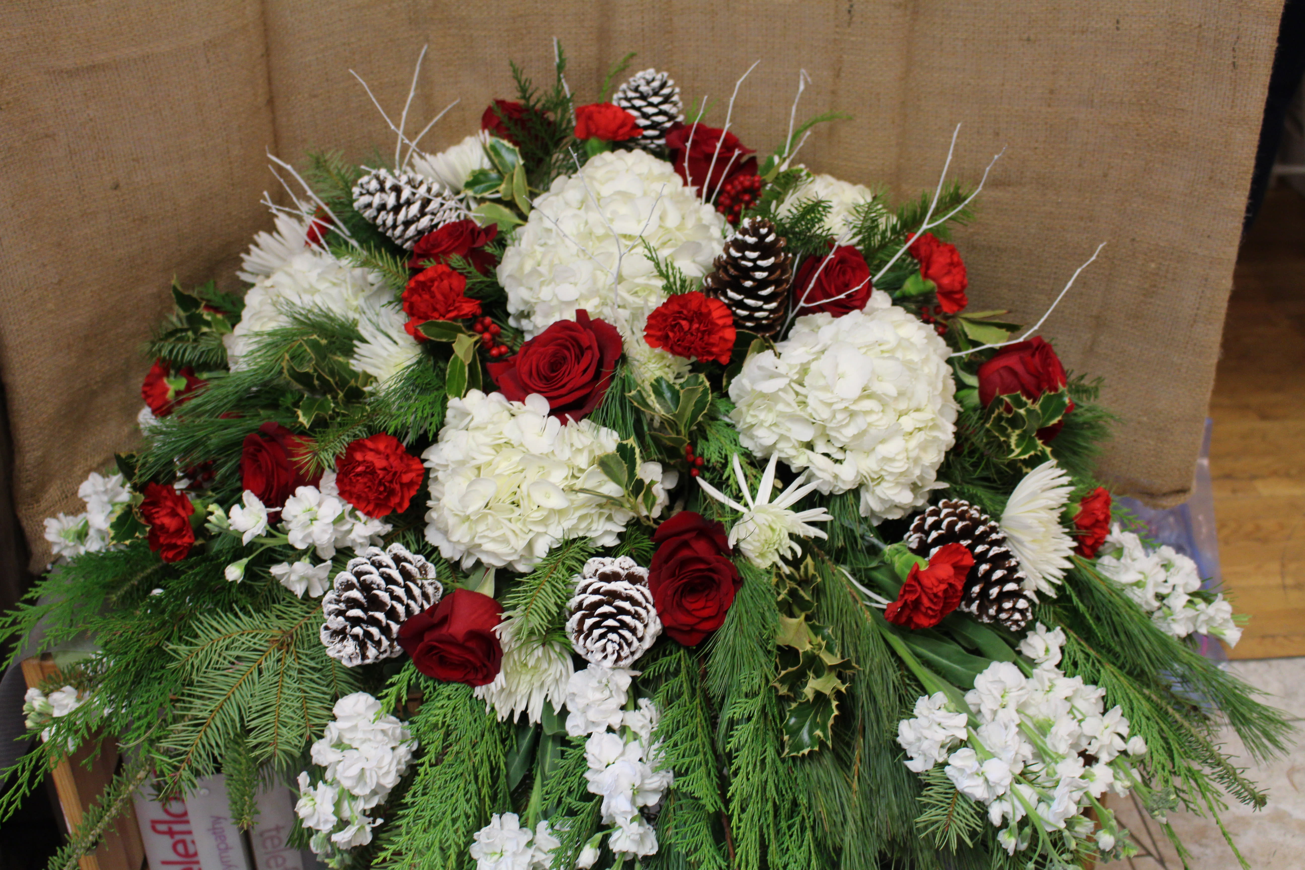 Seasonal Casket Cover - this is a breathtaking Casket spray filled with roses, carnations, hydrangea, pinecones and twigs.  