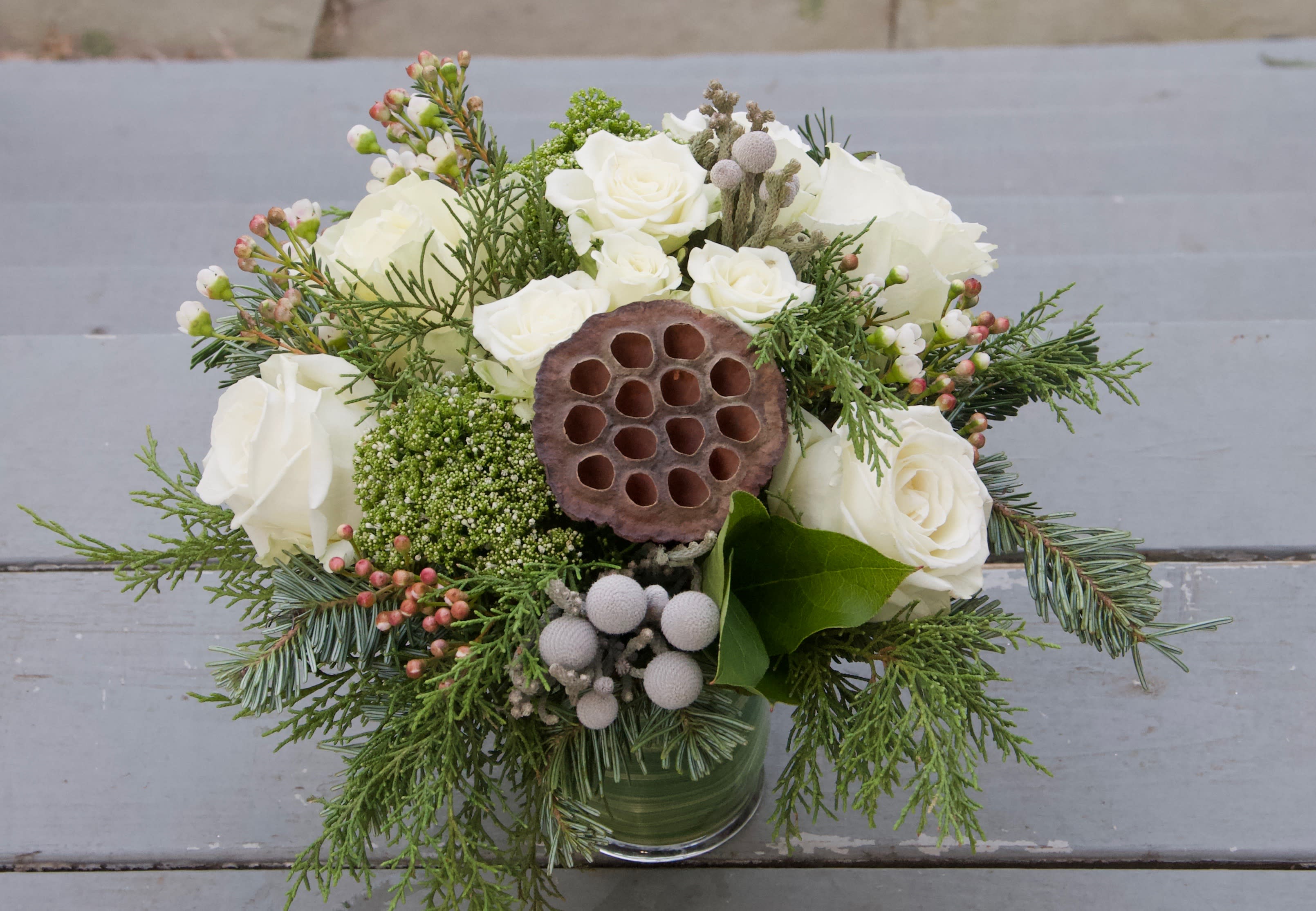 Seasonal Arrangement - Winter white - A lovely winter themed arrangement featuring white flowers with evergreens and a variety of winter textures and frosty blue accents. This arrangement may include some dried elements to add to the wintery forest feel.