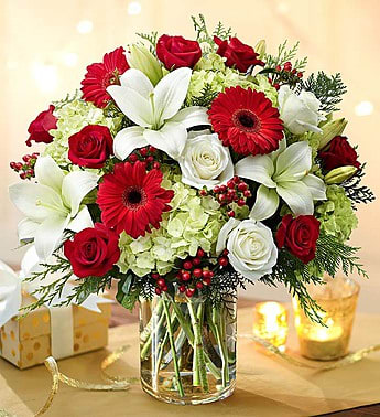 Grand Holiday Garden - Send the biggest and best holiday surprise they’ve ever seen! This lush, jubilant bouquet features an exquisite mix of roses, lilies, Gerbera daisies and green hydrangeas, hand-designed by our expert floral designers inside a glass cylinder vase with fragrant assorted Christmas greens to celebrate the season in luxurious style!