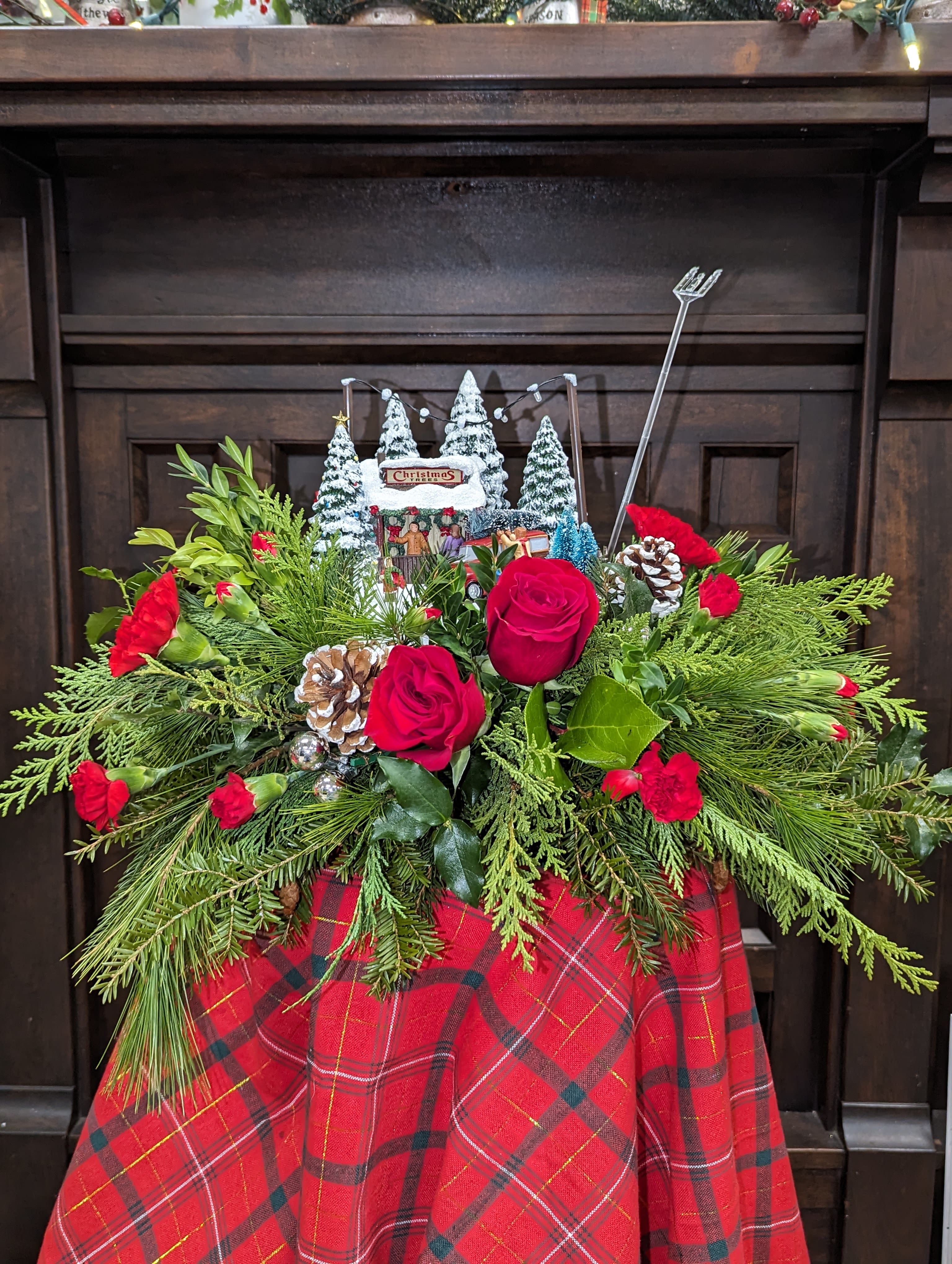 Christmas Village Center Piece  - Long and low in style with assorted Christmas village scenes. Done with a mix of Christmas greens and seasonal flowers
