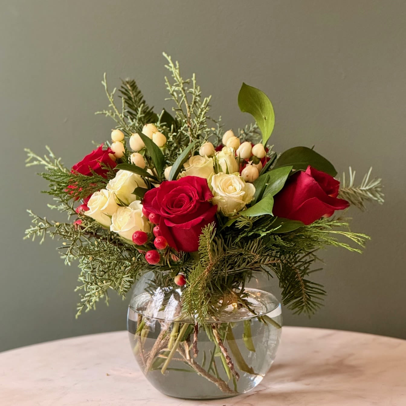 Winter Elegance - Red, white, and green floral arrangement. Featuring: - Ecuadorian Roses - Spray Roses - Hypericum - Styled with premium seasonal foliage Presentation Options: Clear bowl measuring approximately 6&quot; H. (bowl included in price) Every order includes: A custom message card - simply enter your message at checkout and we'll take care of the rest. Please note: Flowers are subject to seasonal availability. If a listed flower is unavailable, our designers will substitute it with flowers of a similar shape, color, and style to maintain the overall aesthetic.