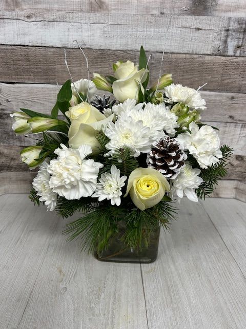 White Christmas - A serene celebration of winter’s beauty, White Christmas features an elegant gathering of all-white blooms arranged with timeless sophistication. Snowy roses, and delicate seasonal accents create a peaceful, glistening look reminiscent of fresh fallen snow. Designed in a clean, modern style, this arrangement brings a touch of winter magic to any space—perfect for holiday gifting, celebrations, or adding a graceful glow to your home for the season.