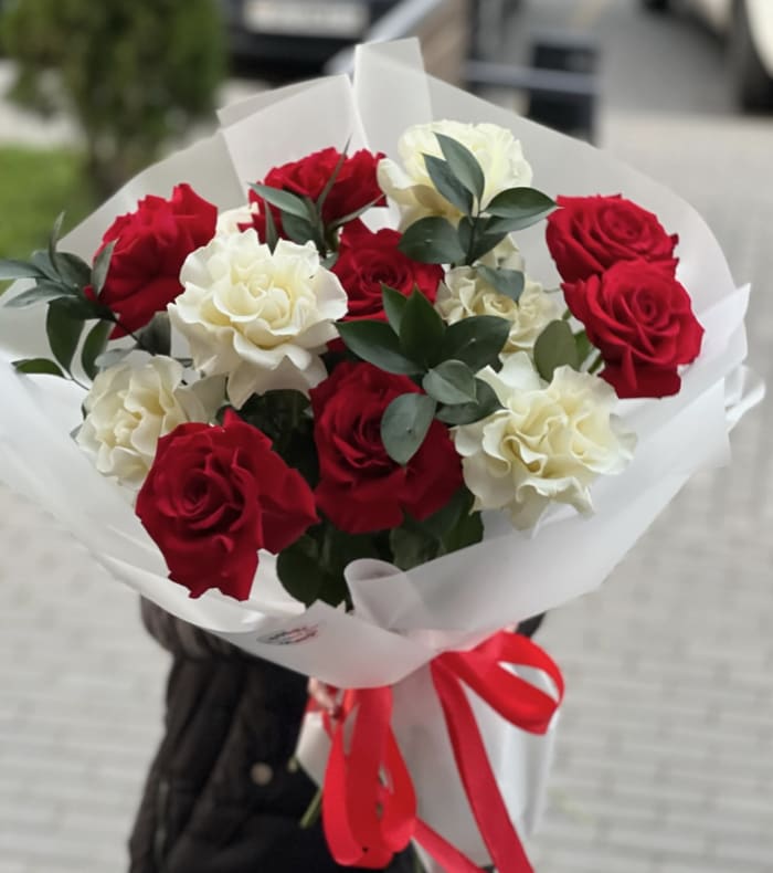 Red and White Open Roses - Standard: 1 Dozen  Deluxe: 2 Dozen Premium: 3 Dozen This bouquet is an exquisite harmony of passion and purity- luscious red roses paired with creamy white blooms for a striking, timeless contrast. Each stem is carefully arranged to create a balanced composition, where romance meets serenity, and bold color meets soft elegance.  The red roses speak of affection, admiration, and heartfelt devotion, while the white flowers represent sincerity, grace, and new beginnings. Accents of greenery add a fresh, natural texture, giving the arrangement depth and a modern, effortless look. Wrapped in crisp white paper (it can be changed depending on shop collection) and finished with a ribbon, the bouquet feels intentional, refined, and perfectly gifttable- ideal for anniversaries, romantic gestures, birthdays, or simply to brighten someone's day with beauty and meaning. 