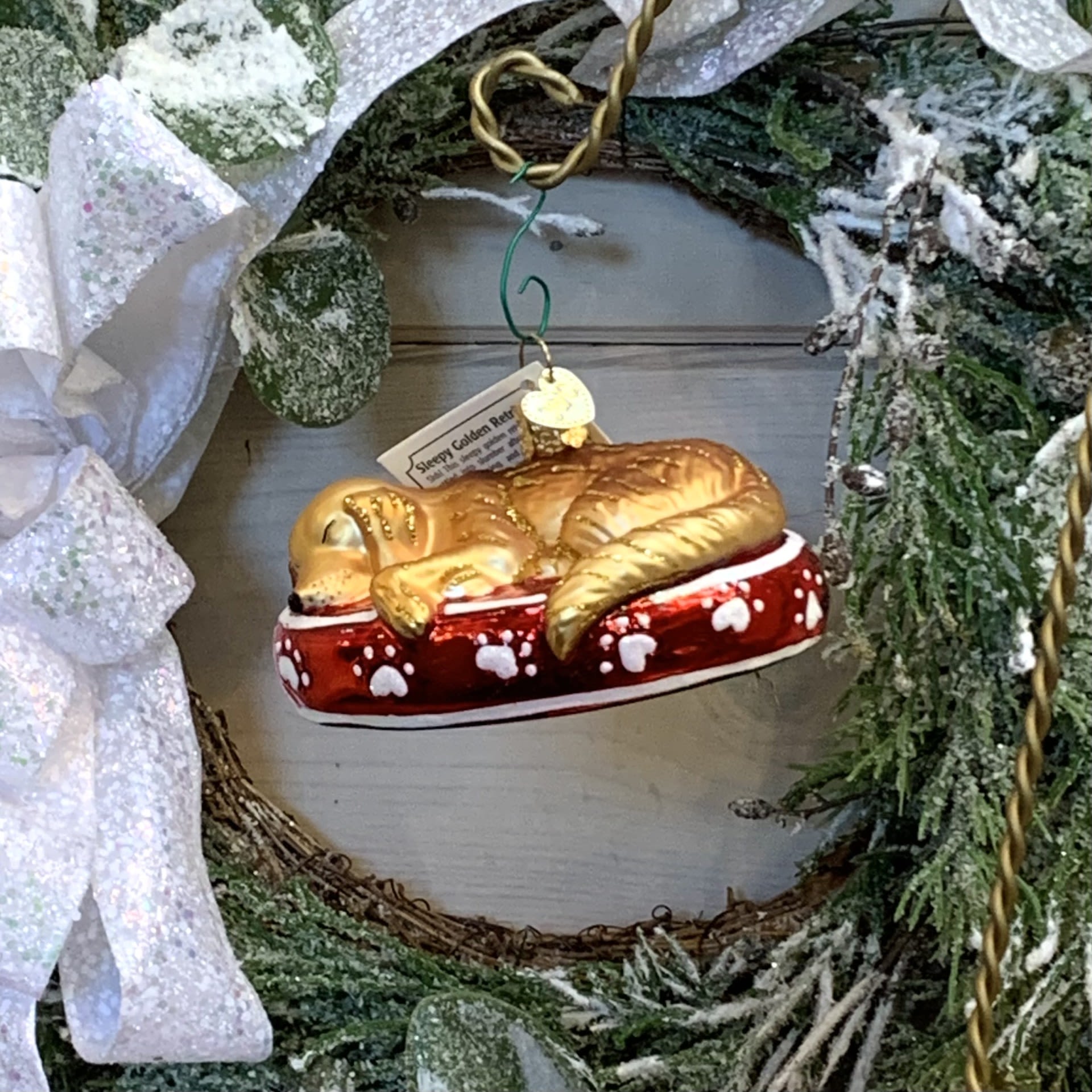 Sleepy Golden Retriever - Shh! This sleepy golden retriever has settled into slumber after a day of running, chasing and fun. Golden retrievers delflessly give humans their unconditional love and attention. Often serving as man's best friend and work assistant, its no wonder golden retrievers are one of the most popular dogs.  Approximately 4" long and 2" tall.  Each figurative glass ornament produced by Old World Christmas is hand crafted in age-old tradition using the same techniques that originated in the 1800s. Molten glass is mouth-blown into finely carved molds made exclusively for Old World Christmas, before a hot solution of liquid silver inpoured inside. The ornaments are then hand-painted and glittered in a series of labor-intensive steps to achieve our beautiful creations.  Wreath and Tree Branch not included.   For more ornaments please check out our store at 3882 Mayberry Dr Ste A, Reno, NV 89519 