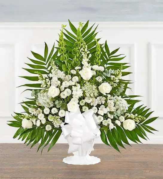Tranquility Basket All White - Offer comfort and tranquility with a truly special display. Our floor basket arrangement is a unique addition to the services, standing over three feet high with lush greenery that cascades out for an elegant presentation. This stylish design is gathered with a flourish of white blooms, creating a beautiful tribute to celebrate their life.Floor basket arrangement with white roses, snapdragons, Peruvian lilies (alstroemeria), Queen Anne’s lace, button poms and stock, green Bells of Ireland; accented with spiral eucalyptus, assorted 