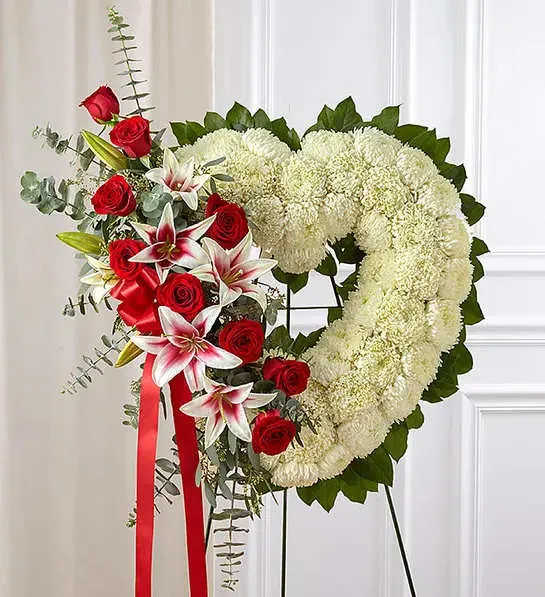 Always Remember Floral Heart Tribute Red Rose &amp; Lily - The passing of someone we love deeply requires a special tribute. Our open heart standing arrangement of fresh white blooms, accented by red roses and Stargazer lilies cascading down one side and adorned with a red satin ribbon, will help you express the devotion and sympathy in your heart.