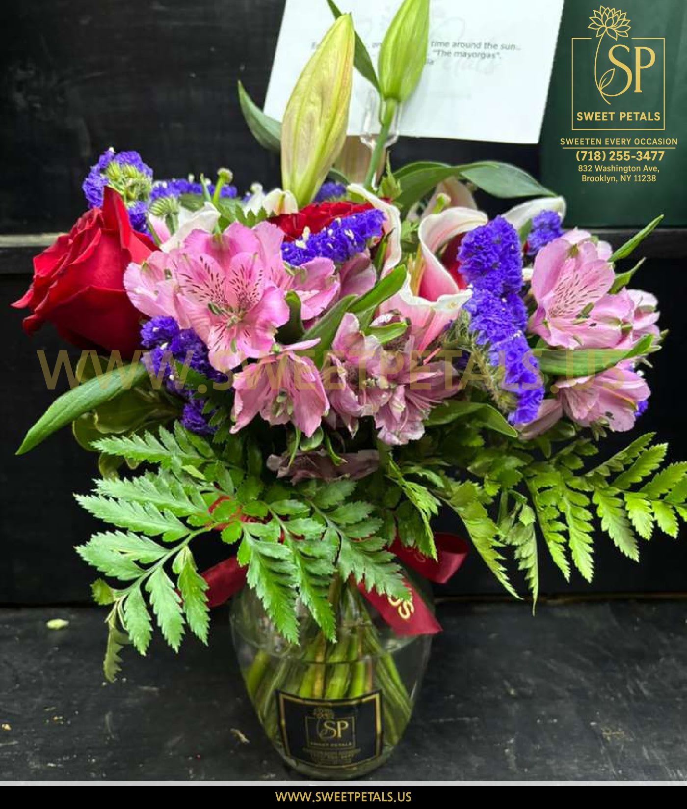 Blossom Harmony Vase Arrangement by SweetPetals - The Blossom Harmony Vase Arrangement by SweetPetals brings together an elegant blend of fresh blooms, thoughtfully arranged to brighten any space and any occasion. Featuring vibrant pink alstroemeria, bold red roses, lush lilies, striking purple statice, and soft seasonal fillers, this arrangement overflows with color, balance, and natural charm.  Hand-designed in a classic SweetPetals glass vase with fresh greens and a signature ribbon, this floral display is perfect for birthdays, anniversaries, thank-you gifts, celebrations, or simply sending love. Each flower is carefully chosen by SweetPetals florists to ensure premium freshness, fragrance, and lasting beauty.  Whether you're surprising someone or decorating your own space, this versatile arrangement is designed to sweeten every occasion.   SweetPetals – Sweeten Every Occasion. 