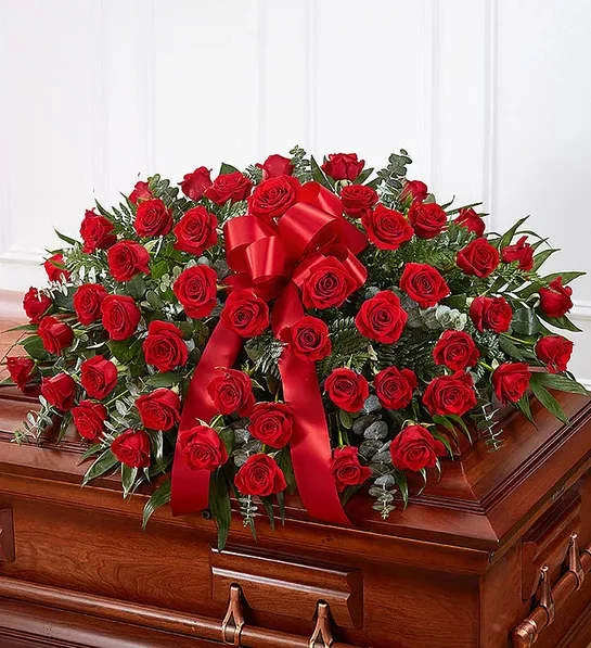 Red Rose Half Casket Cover - When someone near and dear to us passes, it’s natural to want to express all the love and admiration we have in our hearts. Nothing conveys this better than a classic display of red roses. Our half casket cover, crafted with care and artistry by our expert florists with over 50 premium red roses, fresh greenery, and accented with a red satin ribbon, is an unforgettable way to commemorate a lifetime of esteem and adoration.