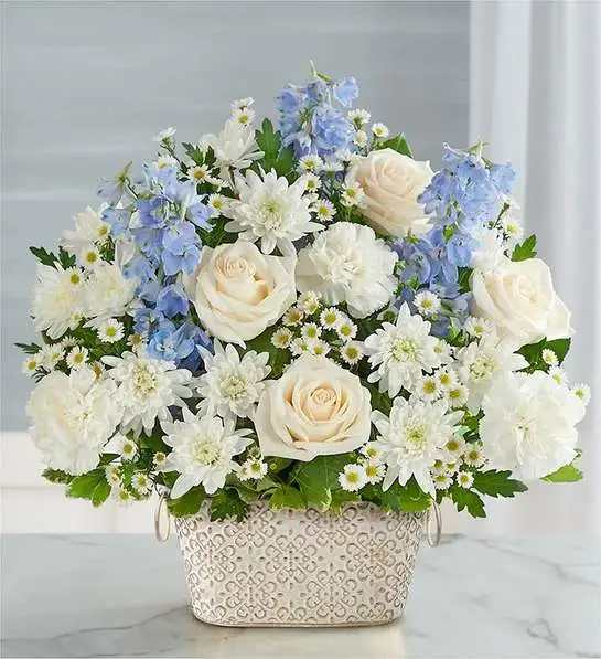 Loving Remembrance  Blue and White - Celebrate the life of a loved one with our beautiful floral tribute. A mix of blooms in soothing shades is a symbol of enduring love. Designed in our Remembrance Cachepot, featuring an embossed pattern and finished with a gold brushed ivory surface.