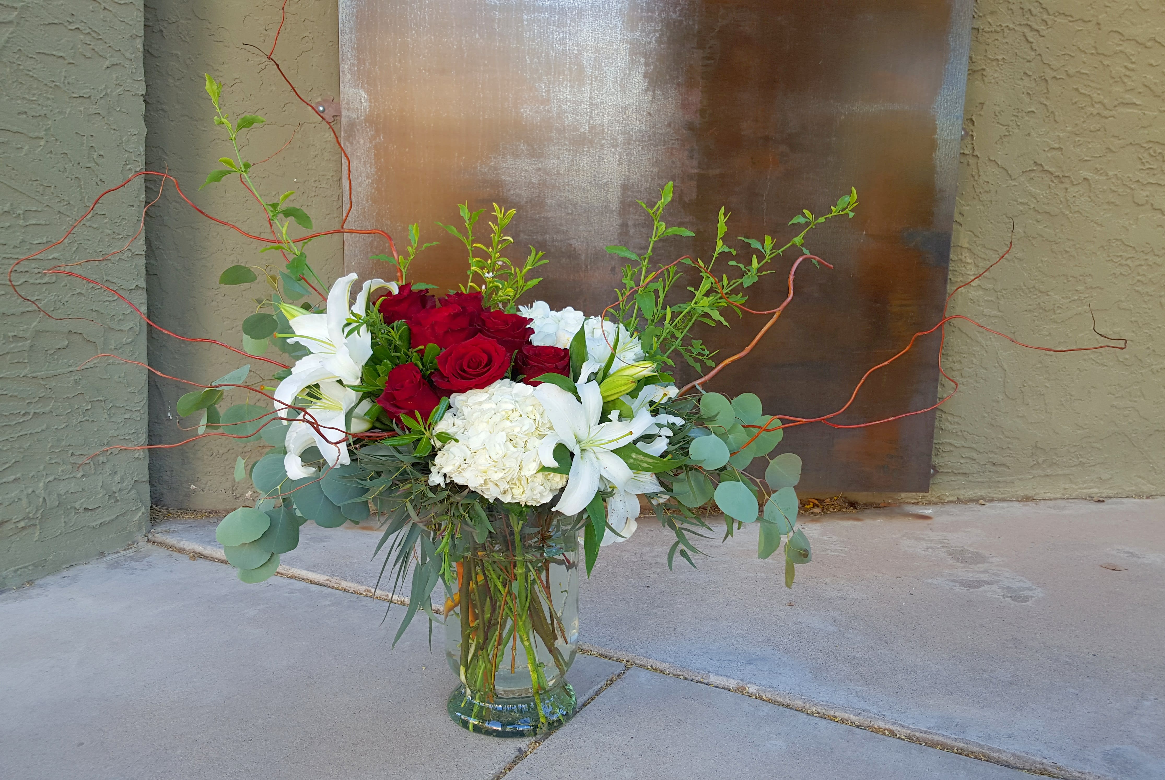 Victorian Story - Fresh picked, from the garden style, this arrangement features red roses and white hydrangea with scented lilies. Upgrades add more flowers and create a bigger arrangement. Measures approx 27&quot; tall and 35&quot; wide. 