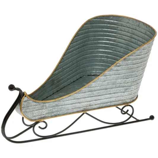 Silver Metal Sleigh - Crafted in ribbed silver-tone metal with a refined gold edge and graceful black scroll runners, this sleigh-shaped accent brings artisan texture and whimsical dimension to consoles, mantels, or tabletops. Style it as a centerpiece or catchall—filled with greenery, florals, rolled towels, or keepsakes—for an eye-catching display any day of the year. Approximate dimensions are 14.5 x 8.25 x 8 inches.