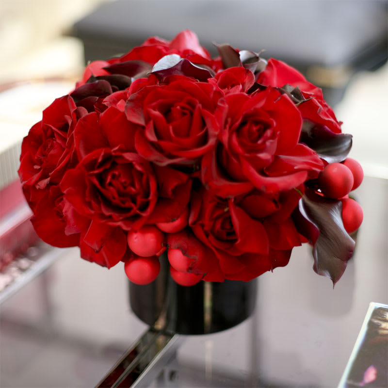 Red Hot Xmas - Red roses and black calla lilies adorned with playful matching ornaments in a simple black vase; perfect for adding a little spice to those on the naughty list! 