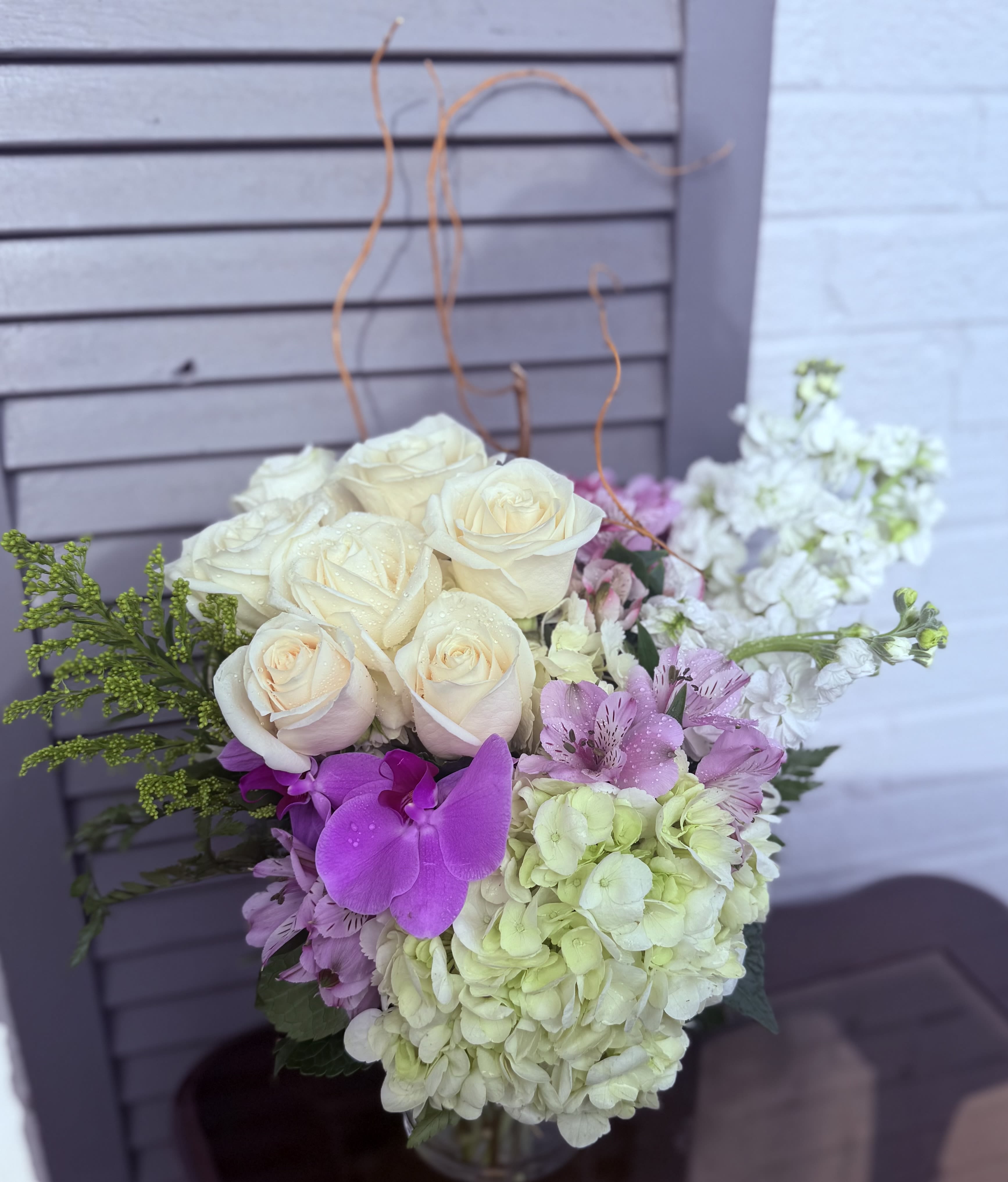 All Precious Flowers  - This chic arrangement has graceful movement and artistic style. Filled with greens, orchids, roses and more, all precious flowers is the breath of fresh air everybody needs. Perfect for all occasions from new baby to happy birthday, this arrangement exudes taste and will be sure to impress.   APPROXIMATE DIMENSIONS 18" W X 18" H