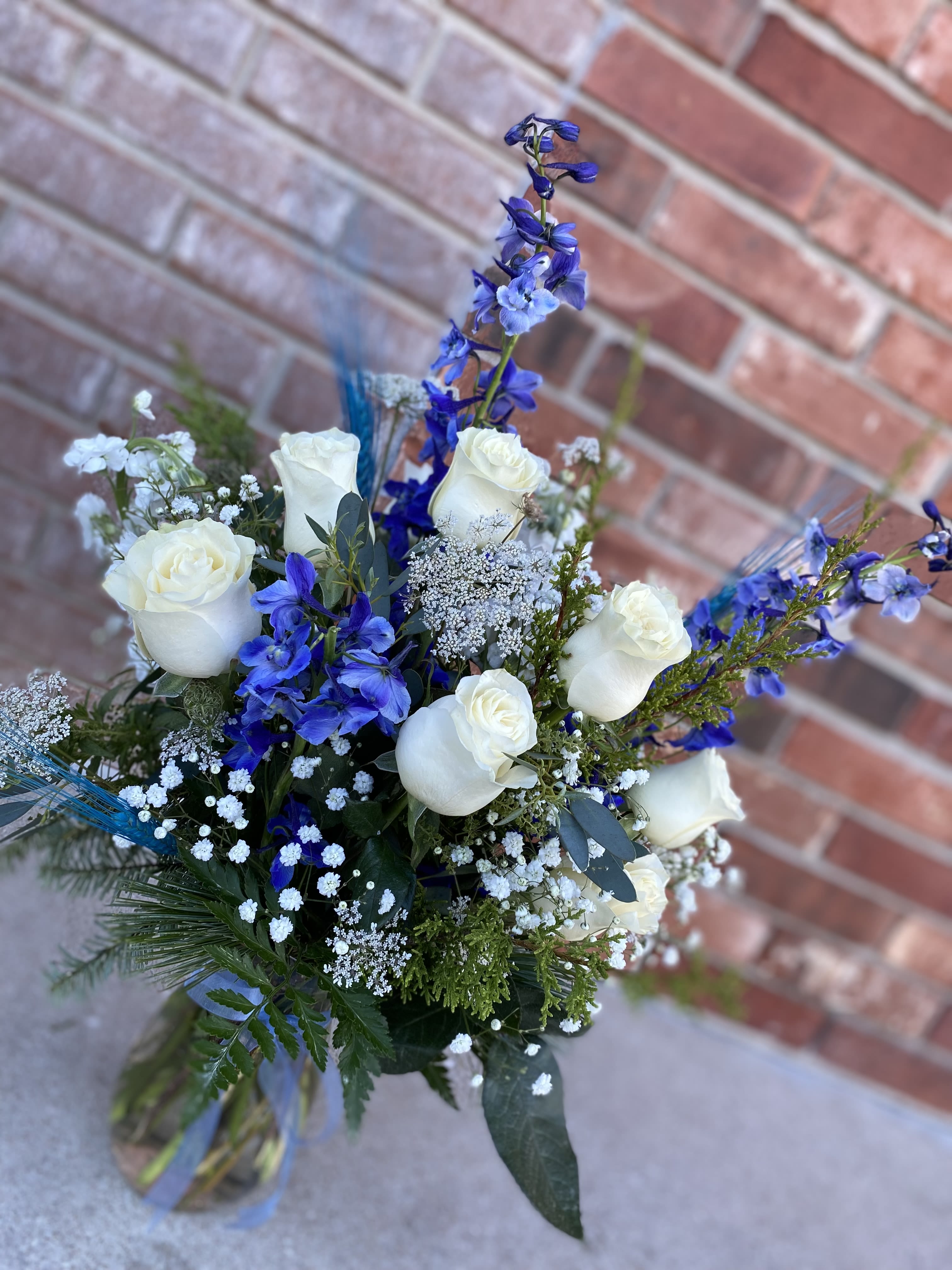 Snowfall and Sapphire  - Roses and vivid blue Delphinium, softened with delicate clouds of babies breath. This white and blue arrangement evokes calm, elegance, and timeless, beauty. Lush greenery, and air texture, bring depth and movement, making it perfect for celebrations, sympathy, or sympathy or simply bringing a touch of peaceful sophistication to any space.