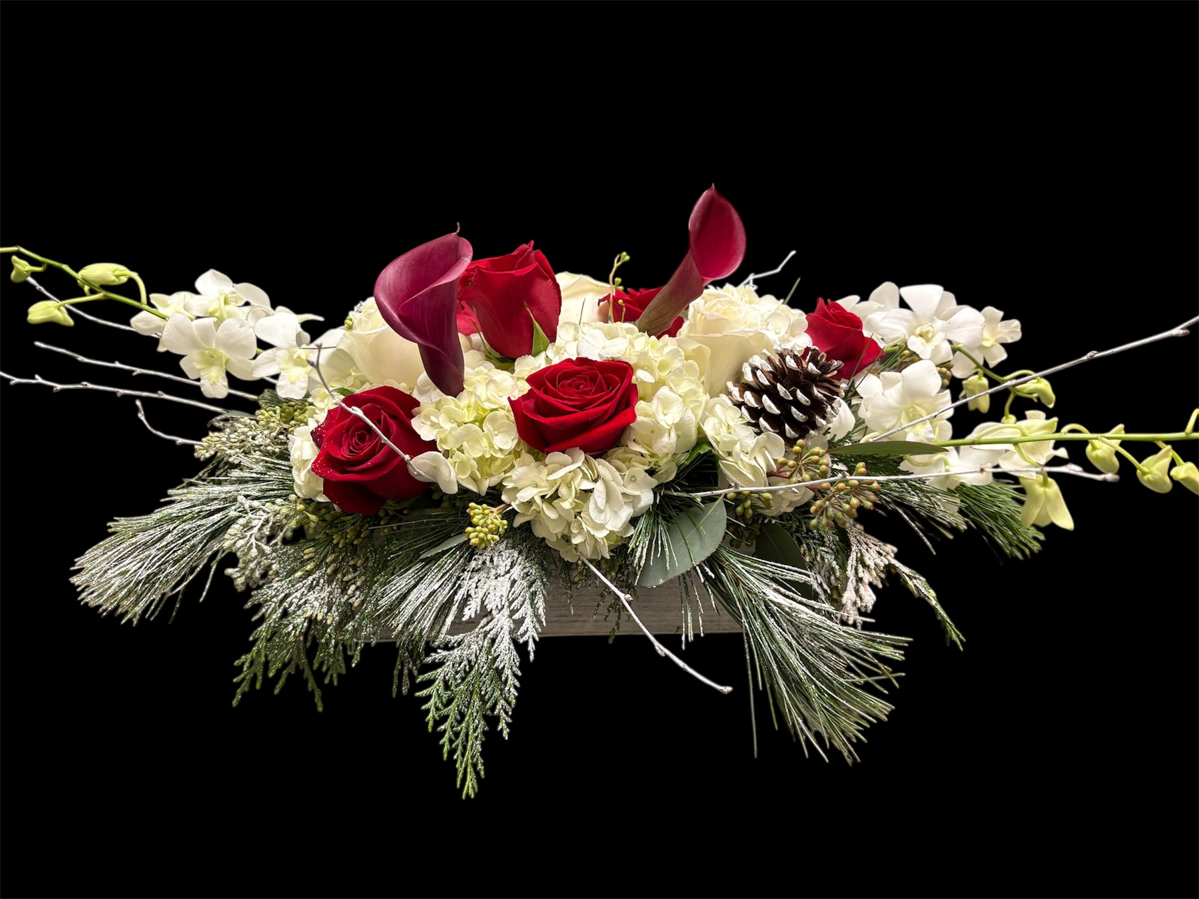 Snowman's Scarf - This unique winter seasonal arrangement arrives with an assortment of fresh flowers inside of a wooden rectangular container to provide that winter look for the holidays. Send this rose and winter greens centerpiece as a lovely home decoration or just because gift. 